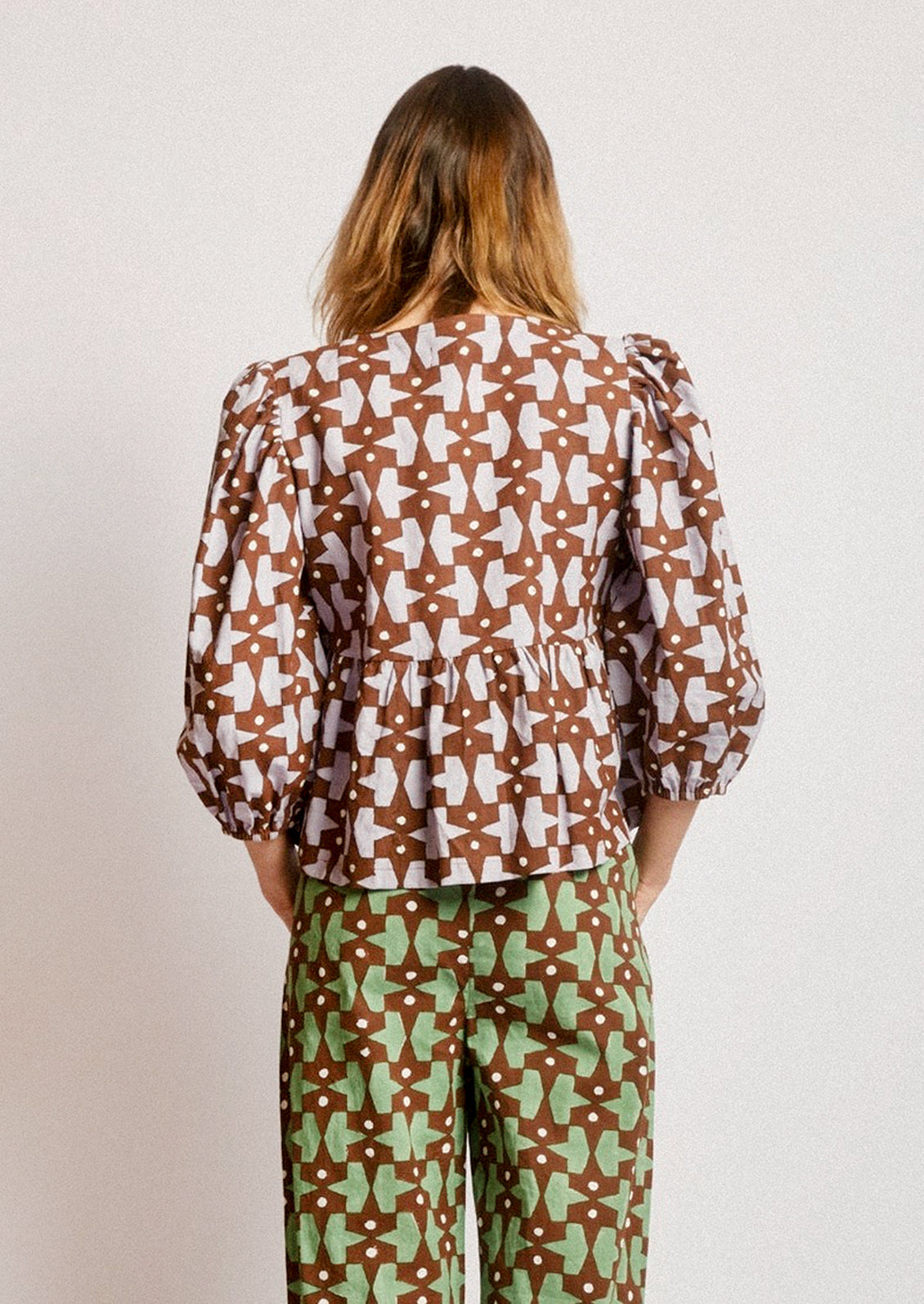 A person wearing a puff sleeve shirt with contrast tie front.