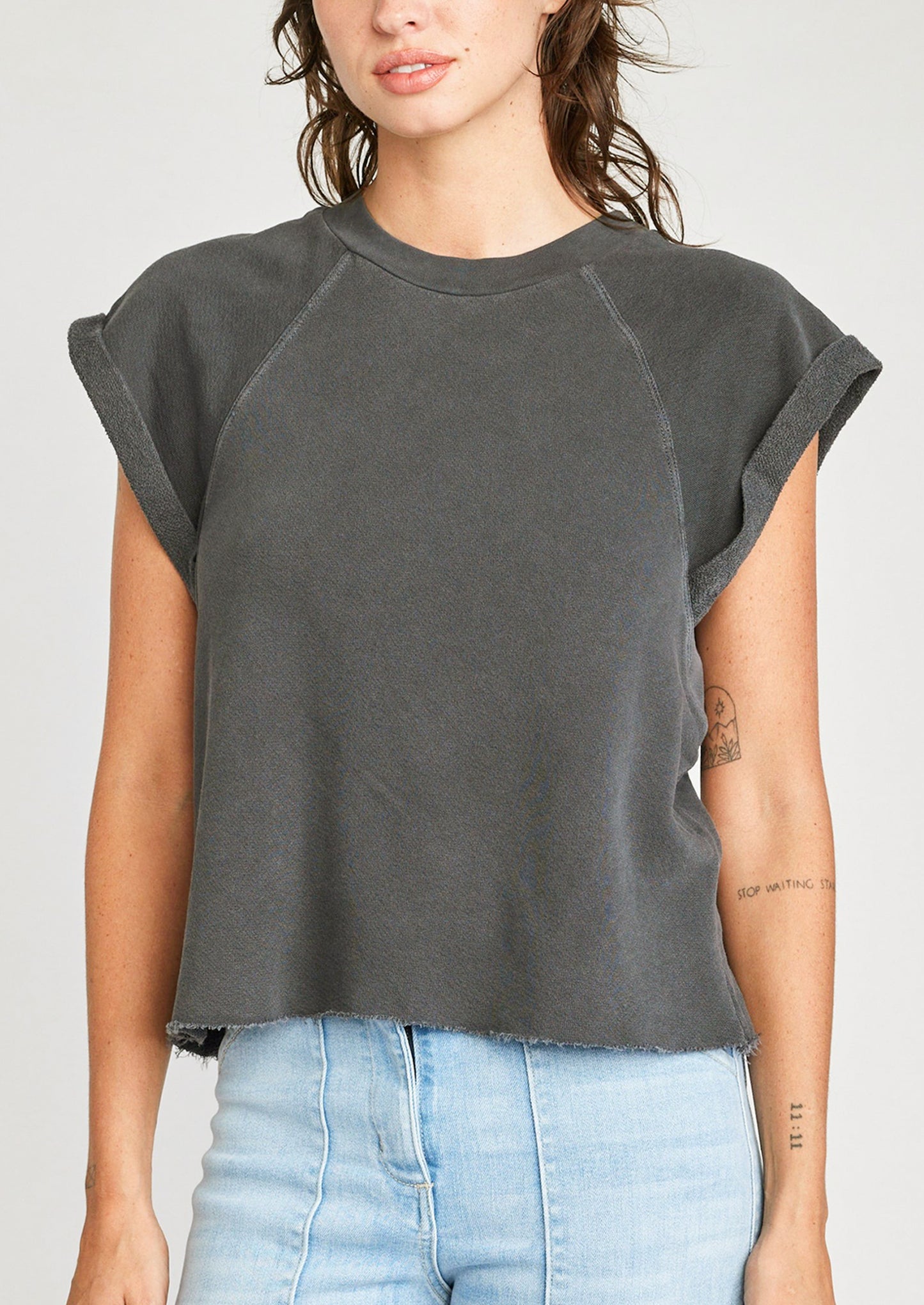 A woman wearing a raglan short sleeve sweatshirt in dark grey.