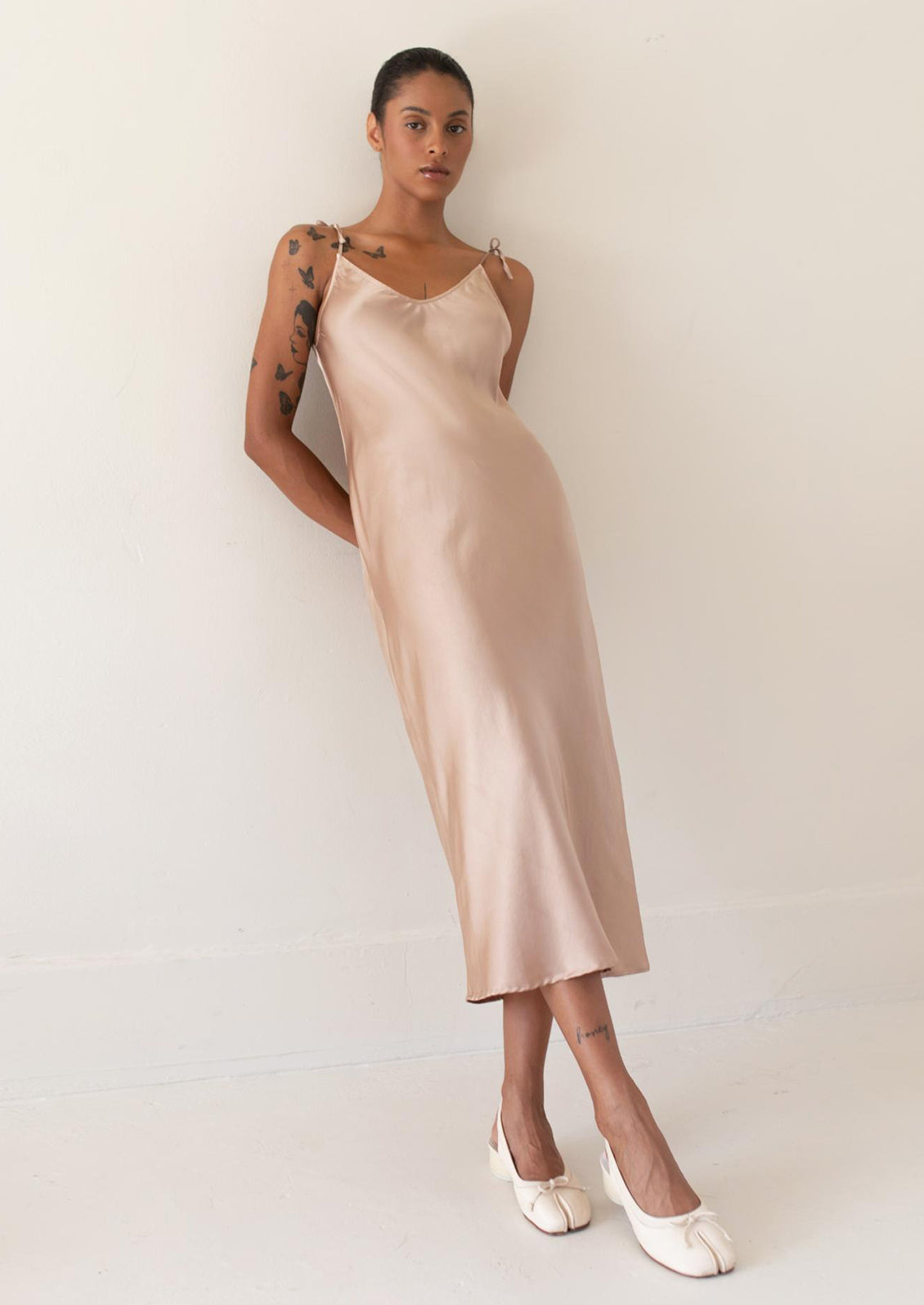 A person wearing a long slinky tank dress in champagne.