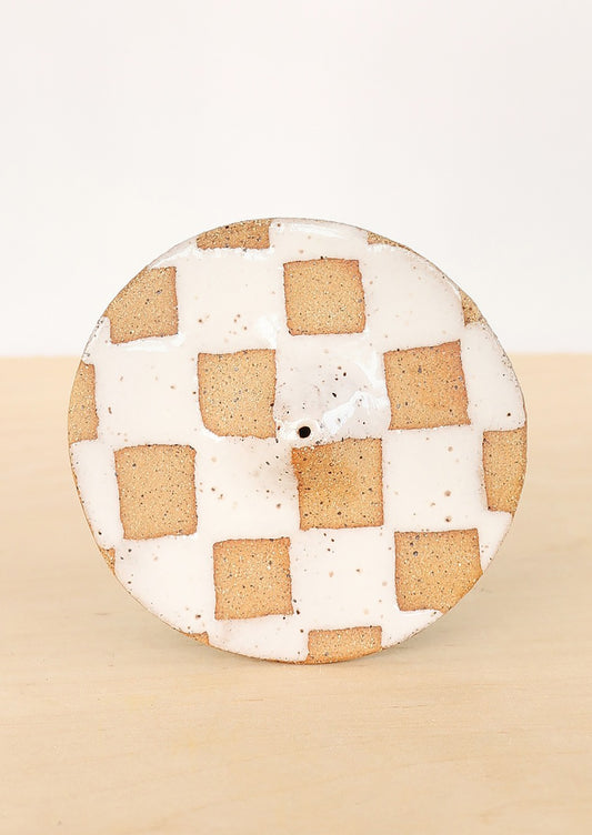 A handmade ceramic incense holder in white checkered pattern.