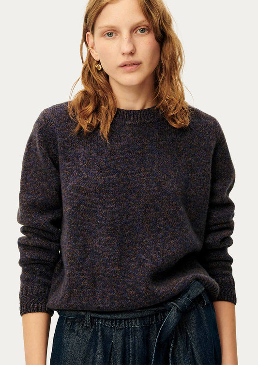 A woman wearing a dark sweater in ink blue melange yarn.