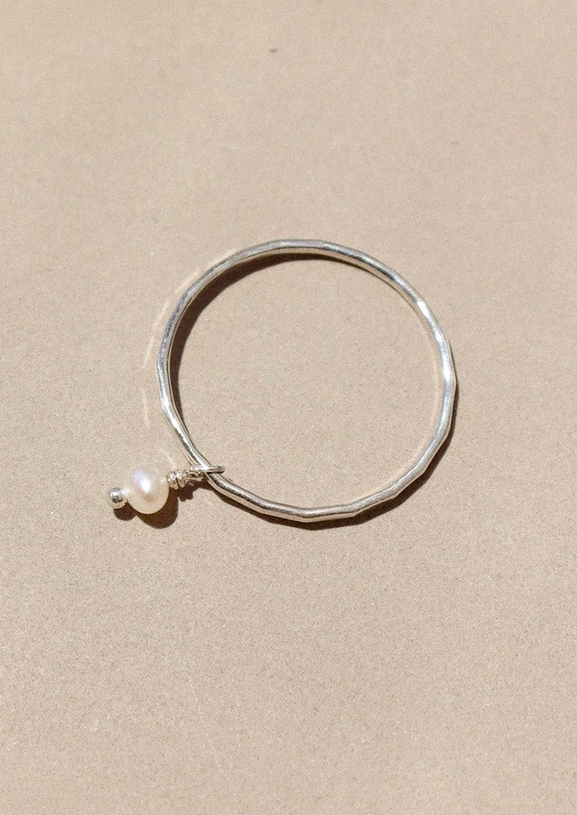 A sterling silver ring with dangling pearl bead.