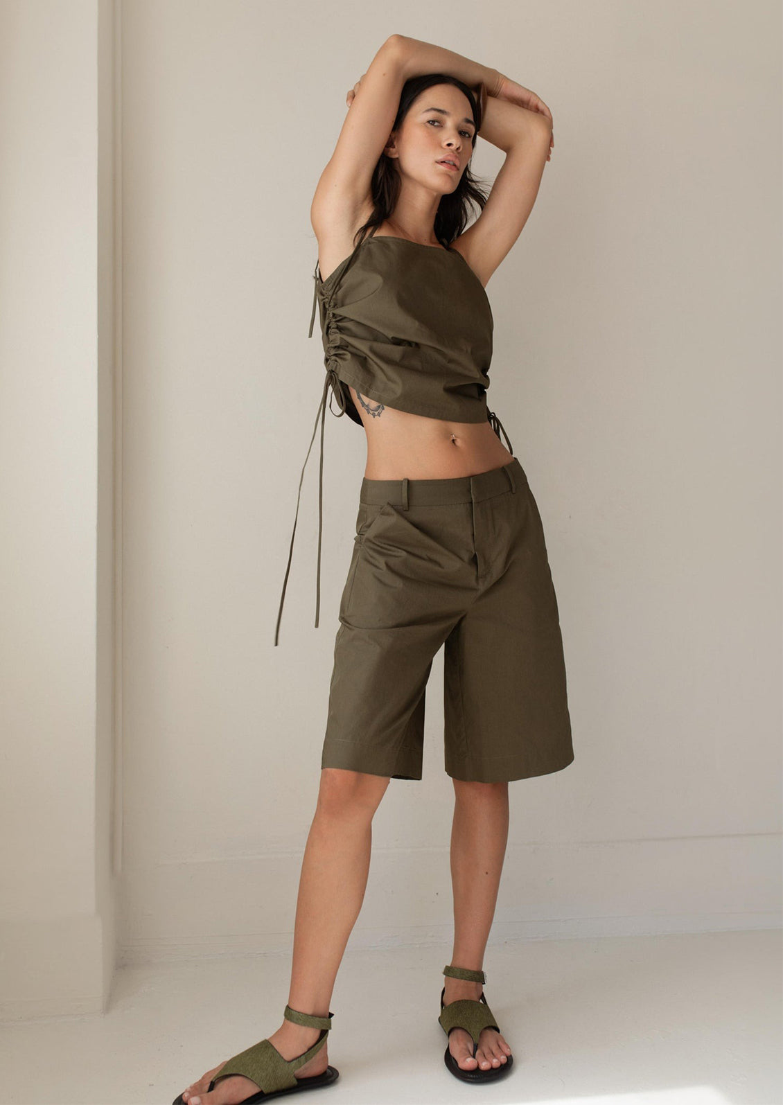 A woman wearing an olive green tank top with scrunched side detail.