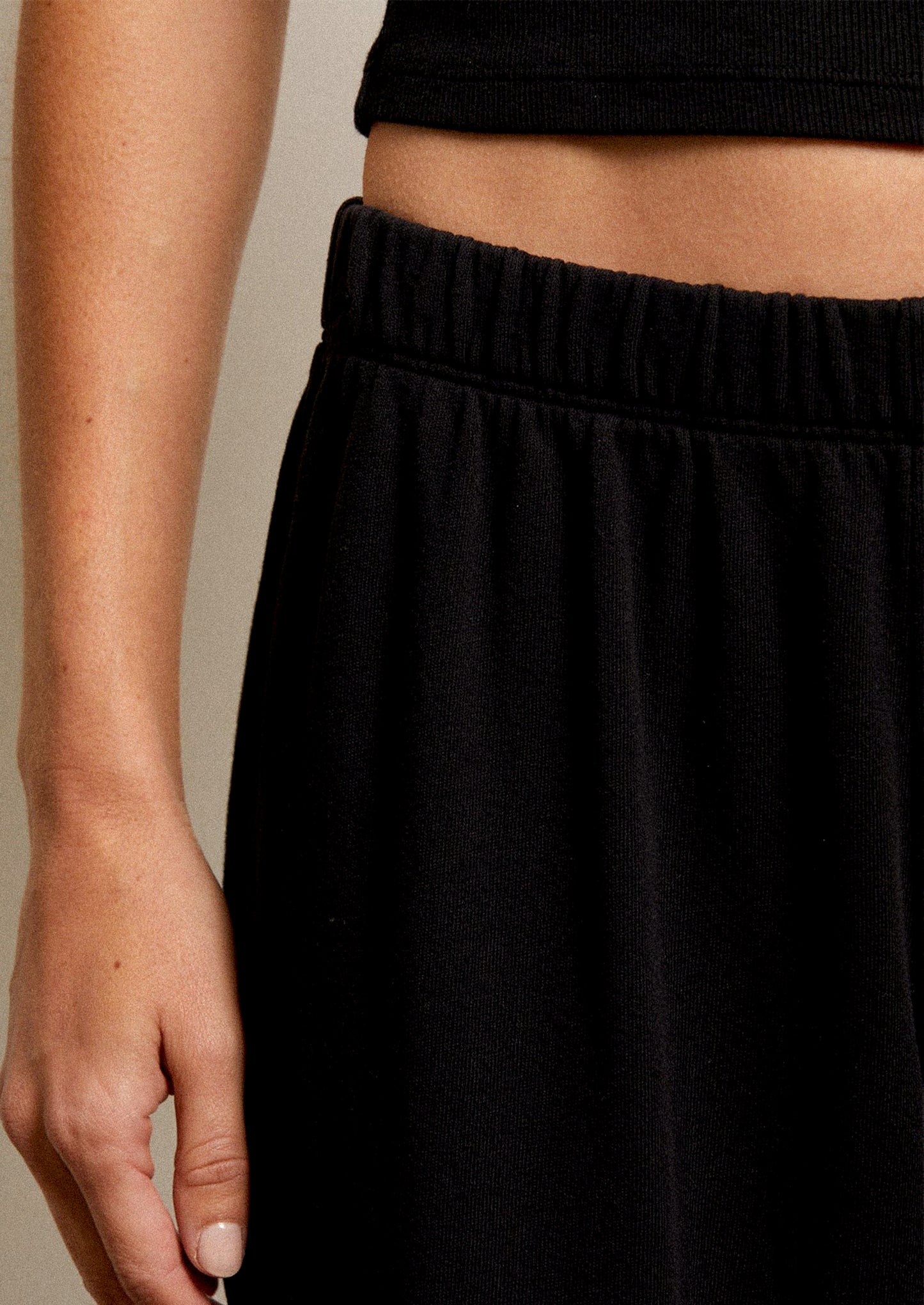 Woman wearing a black sleeveless top and black wide-leg pants.