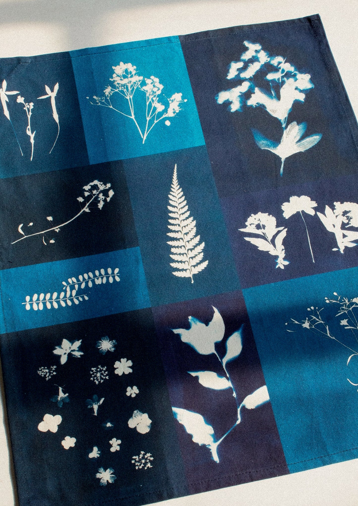 Tea towel with printed white botanical designs on a blue background