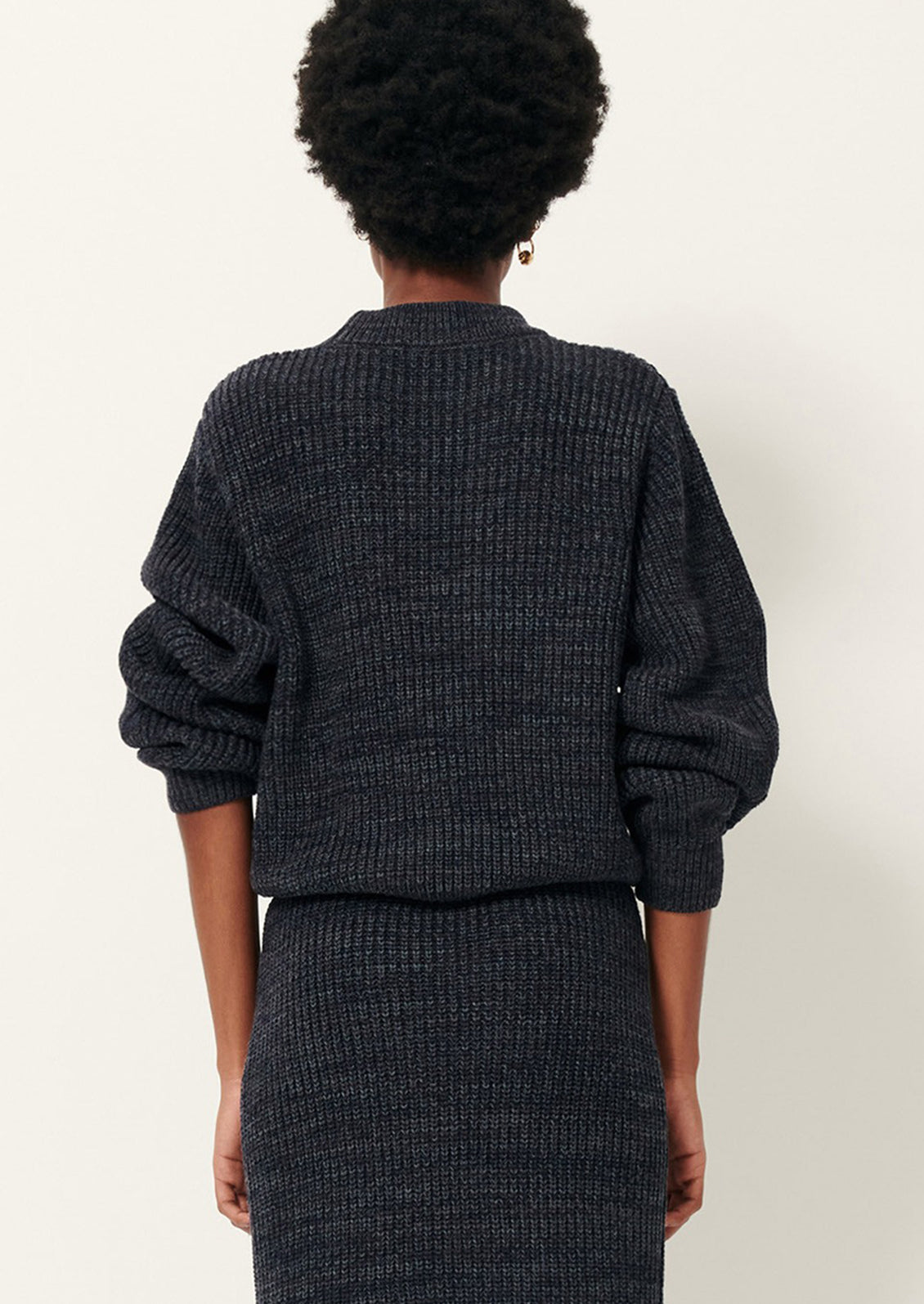 Person wearing a dark gray textured sweater and pants.