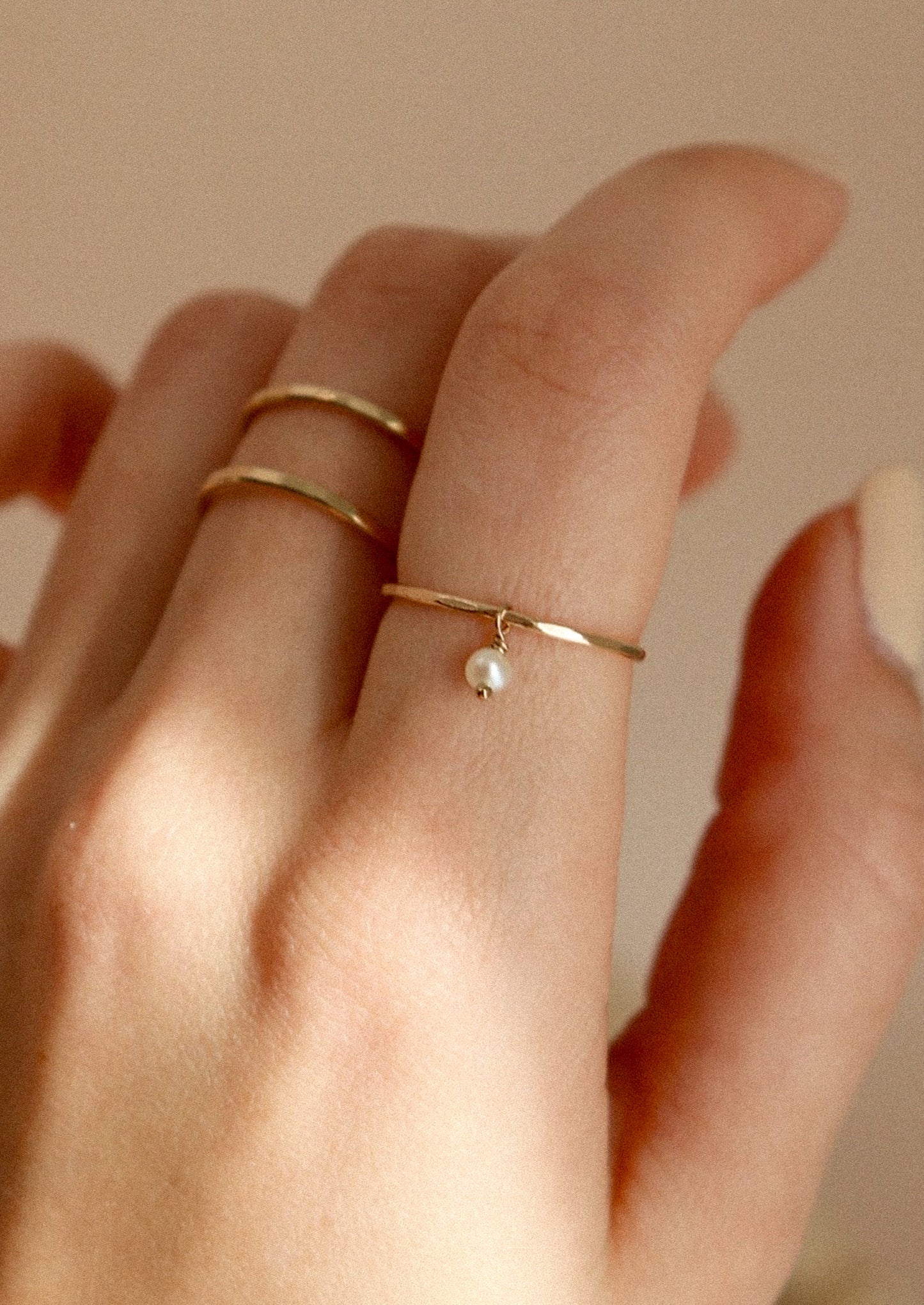 A gold ring with dangling pearl bead.