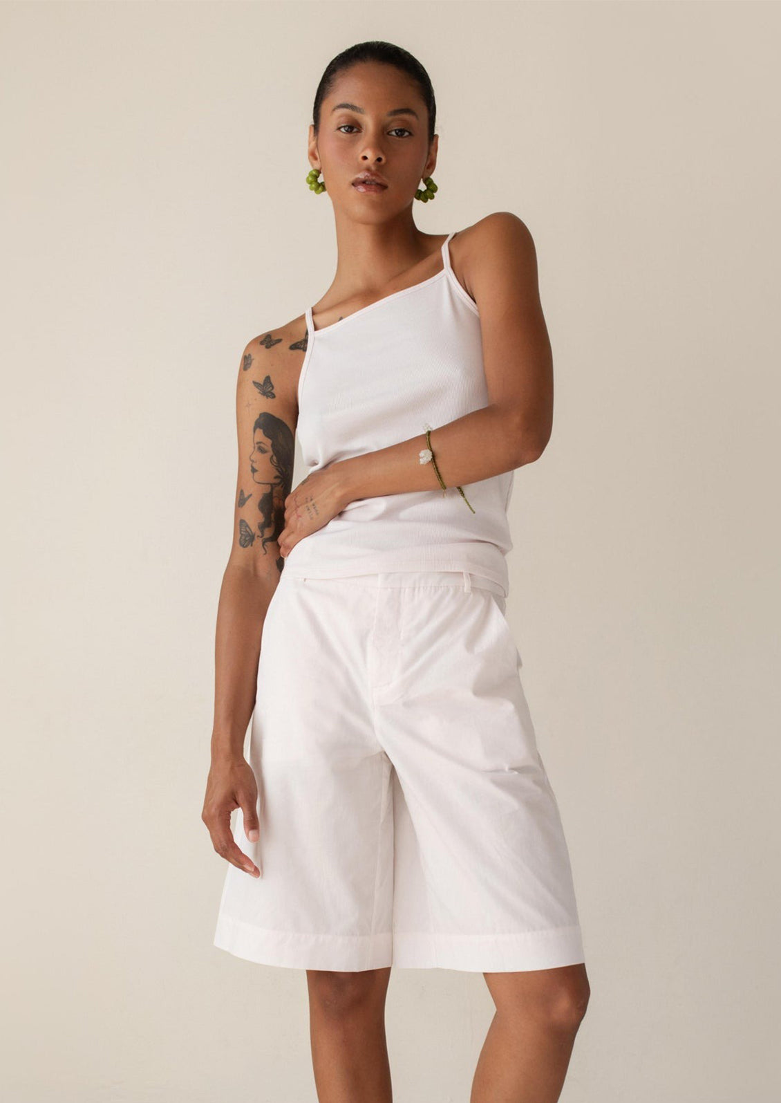 A person wearing a square neck racerback tank top in pale pink.