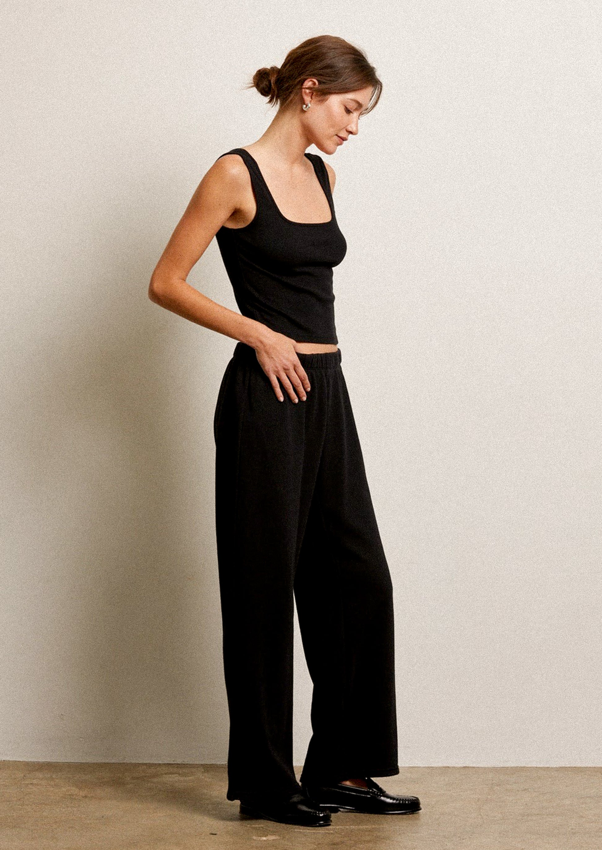 Woman wearing a black sleeveless top and black wide-leg pants.