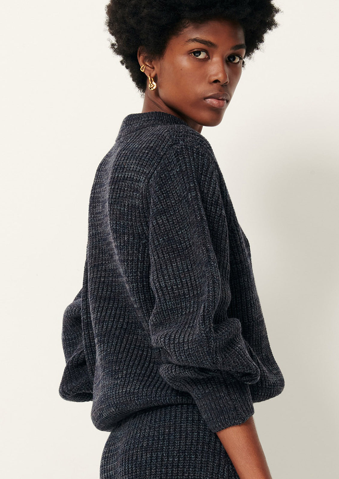 Person wearing a dark gray textured sweater and pants.