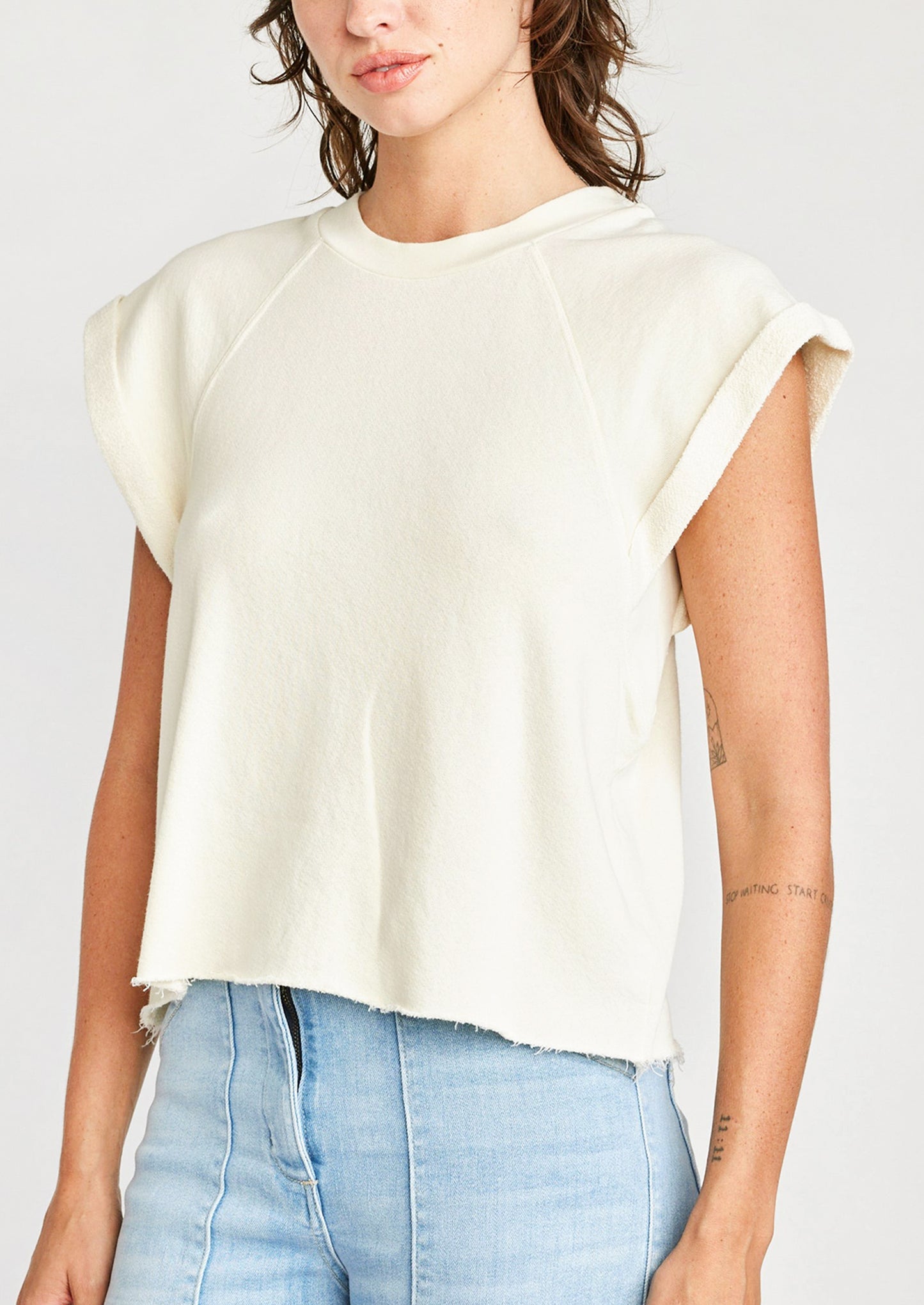 A woman wearing a raglan short sleeve sweatshirt in cream.