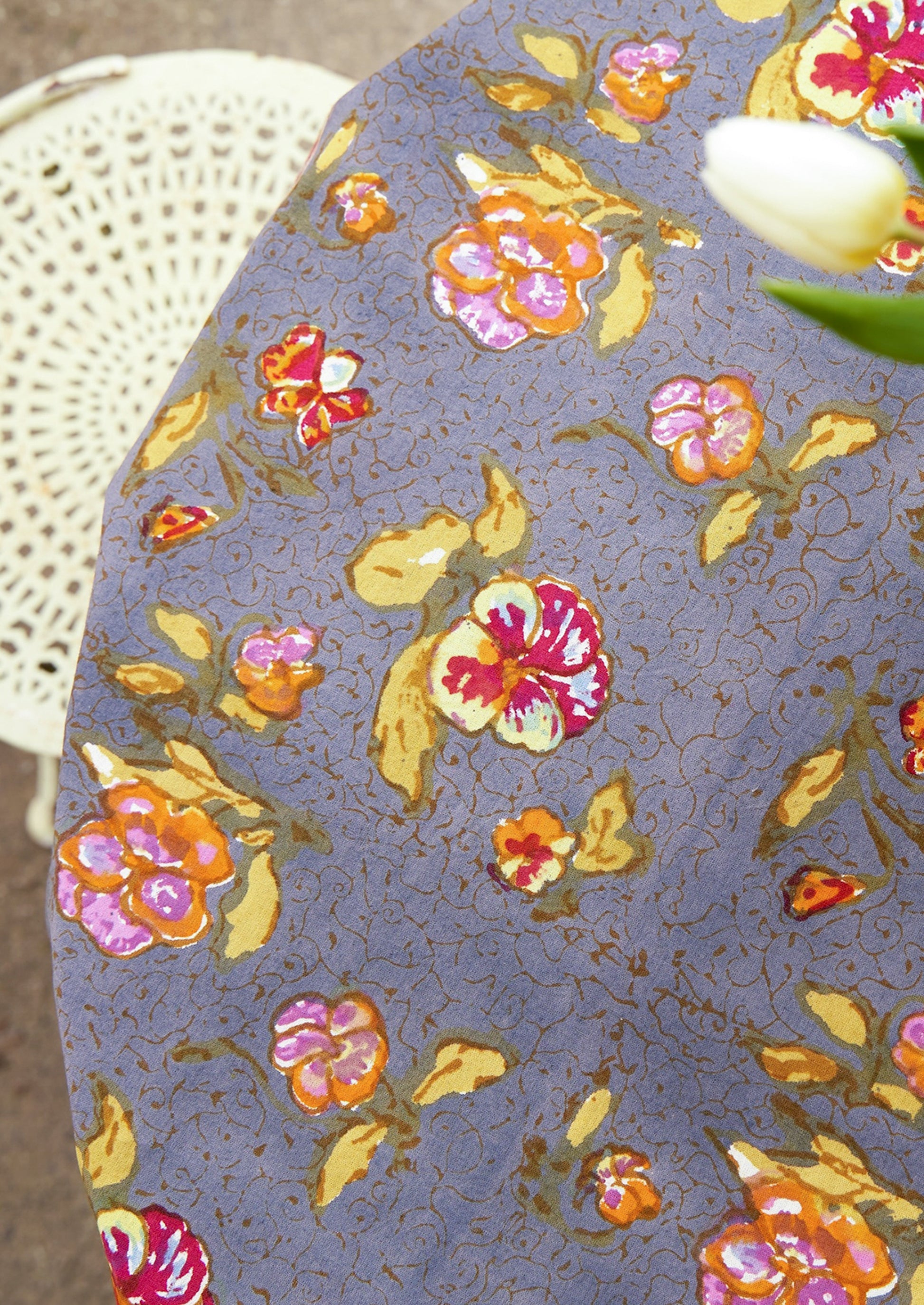 Floral-patterned tablecloth on a round table with a white chair in the background