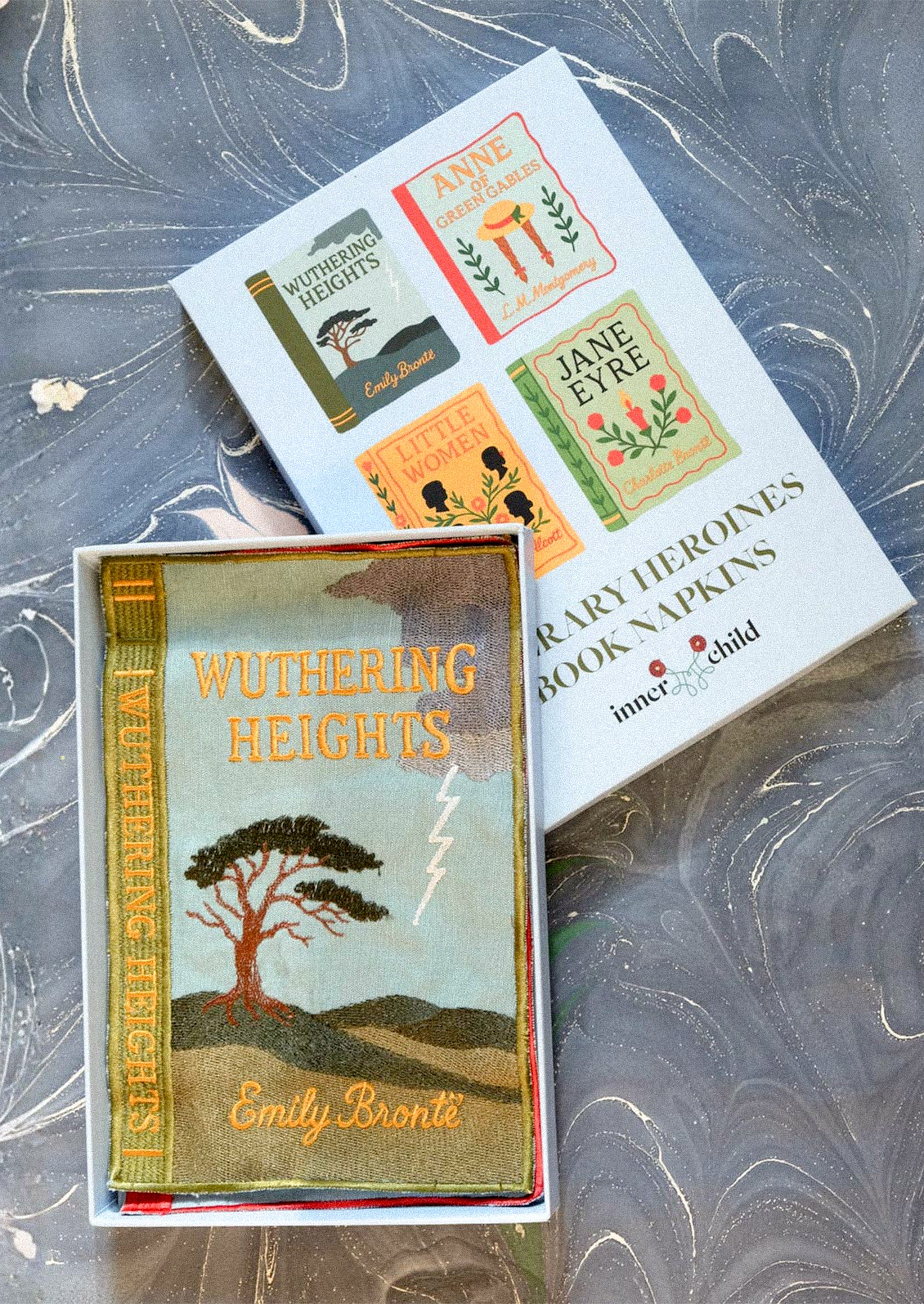 Book napkins with a box labeled 'Literary Heroines Book Napkins' on a textured surface.