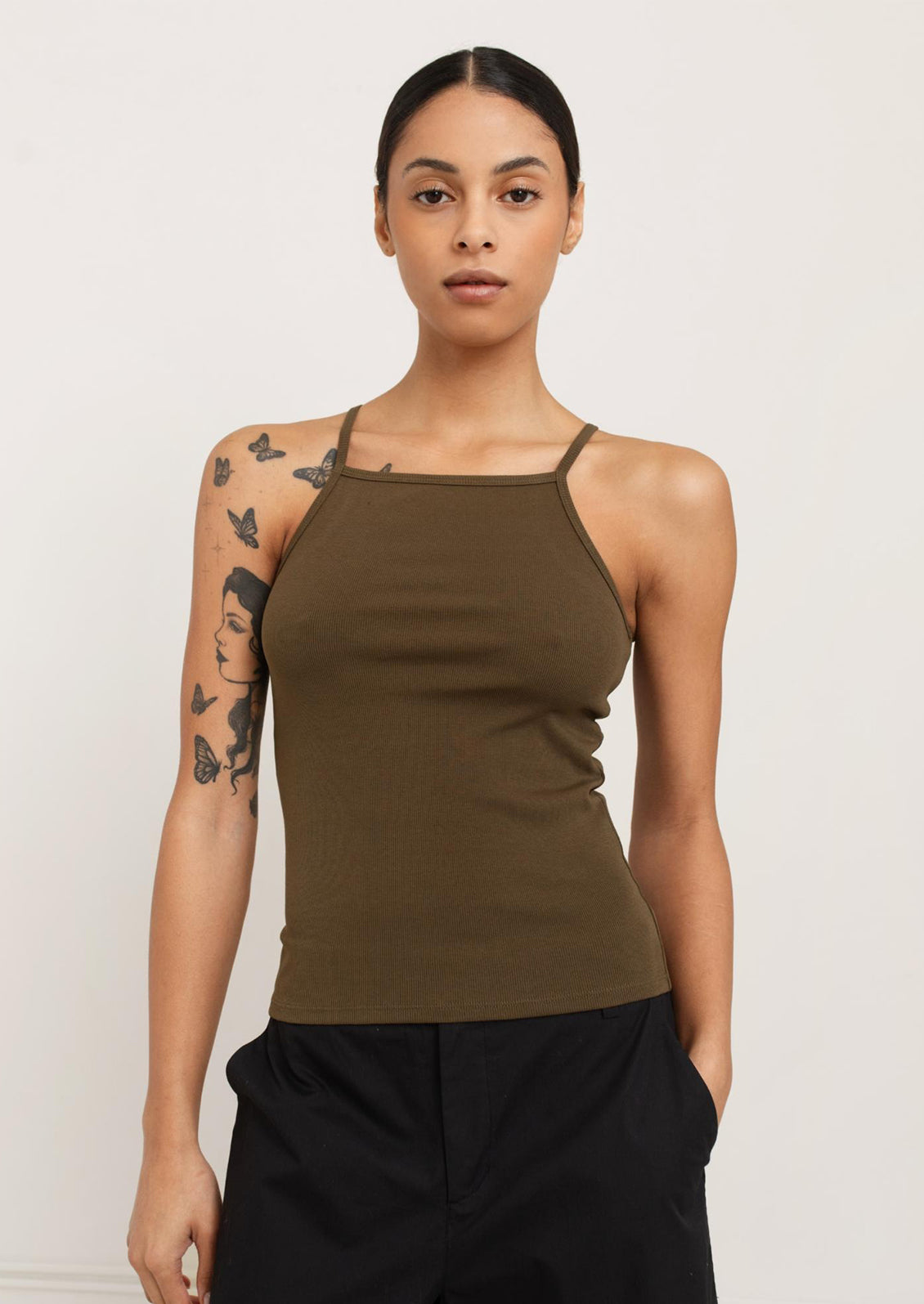 A person wearing a square neck racerback tank top in olive green.
