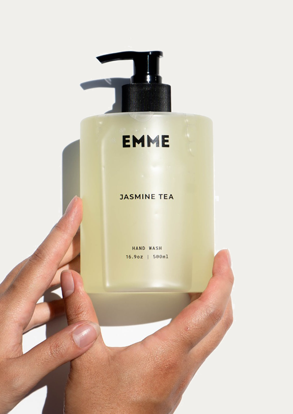 Hand holding a bottle of EMME Jasmine Tea hand wash against a white background