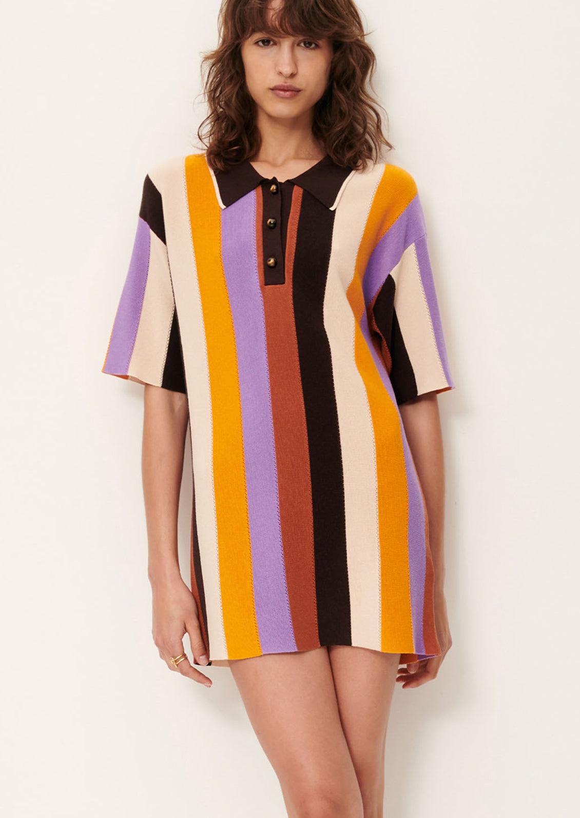 A woman wearing a colorful striped polo dress with short sleeves.