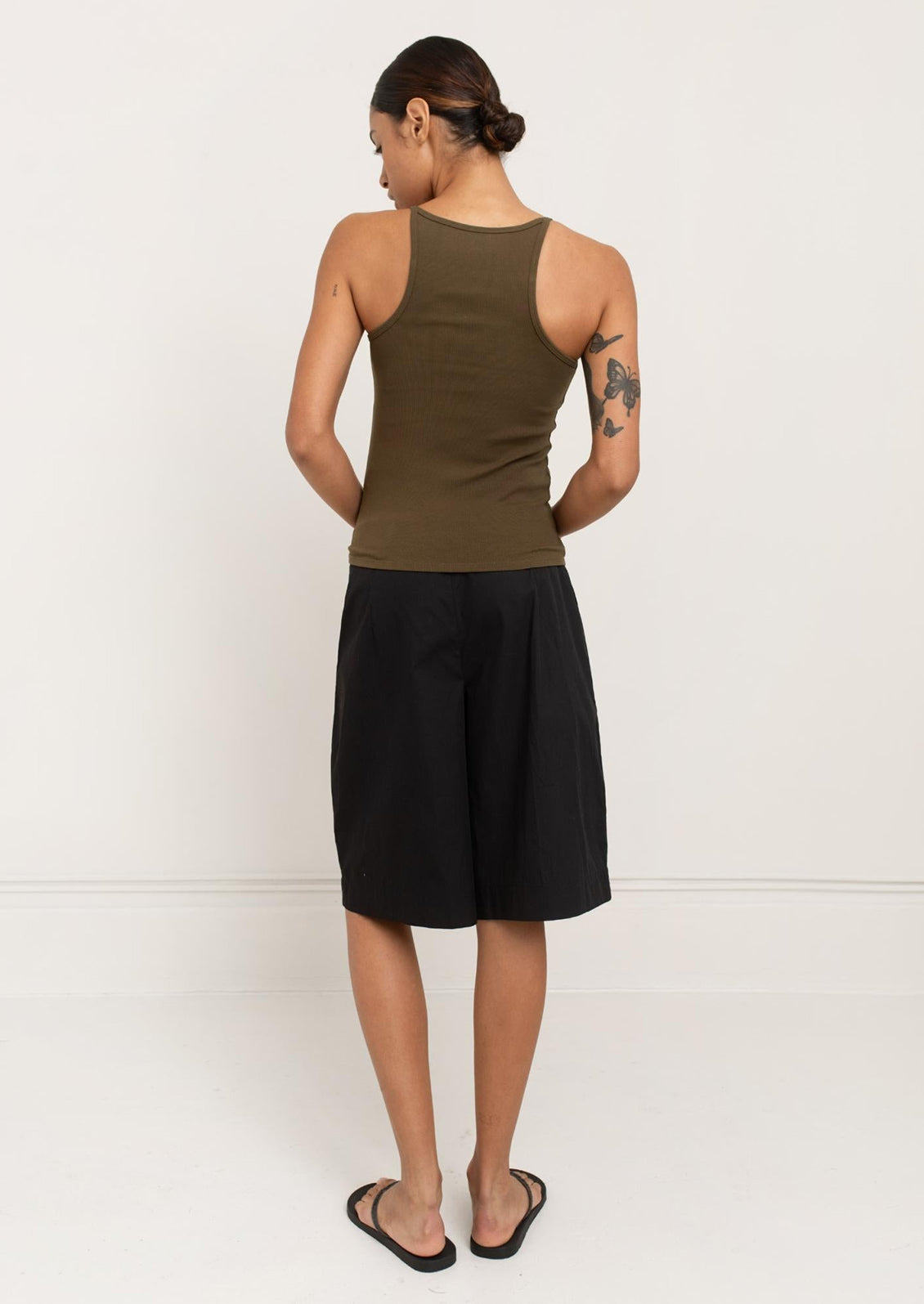 A person wearing a square neck racerback tank top in olive green.