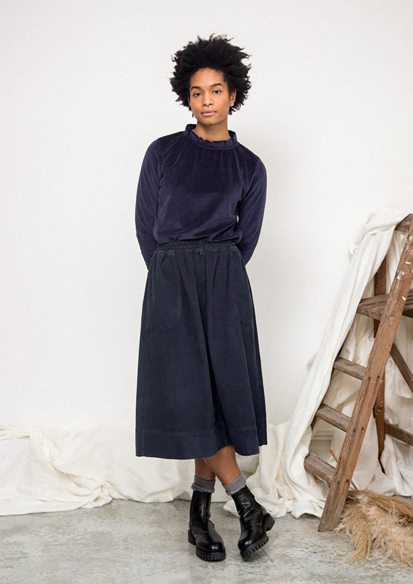 Person wearing a navy blue outfit with a white background