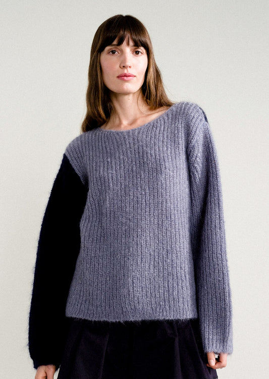 A woman wearing a long sleeve mohair sweater with two-tone colorblocking in dusty blue and navy.