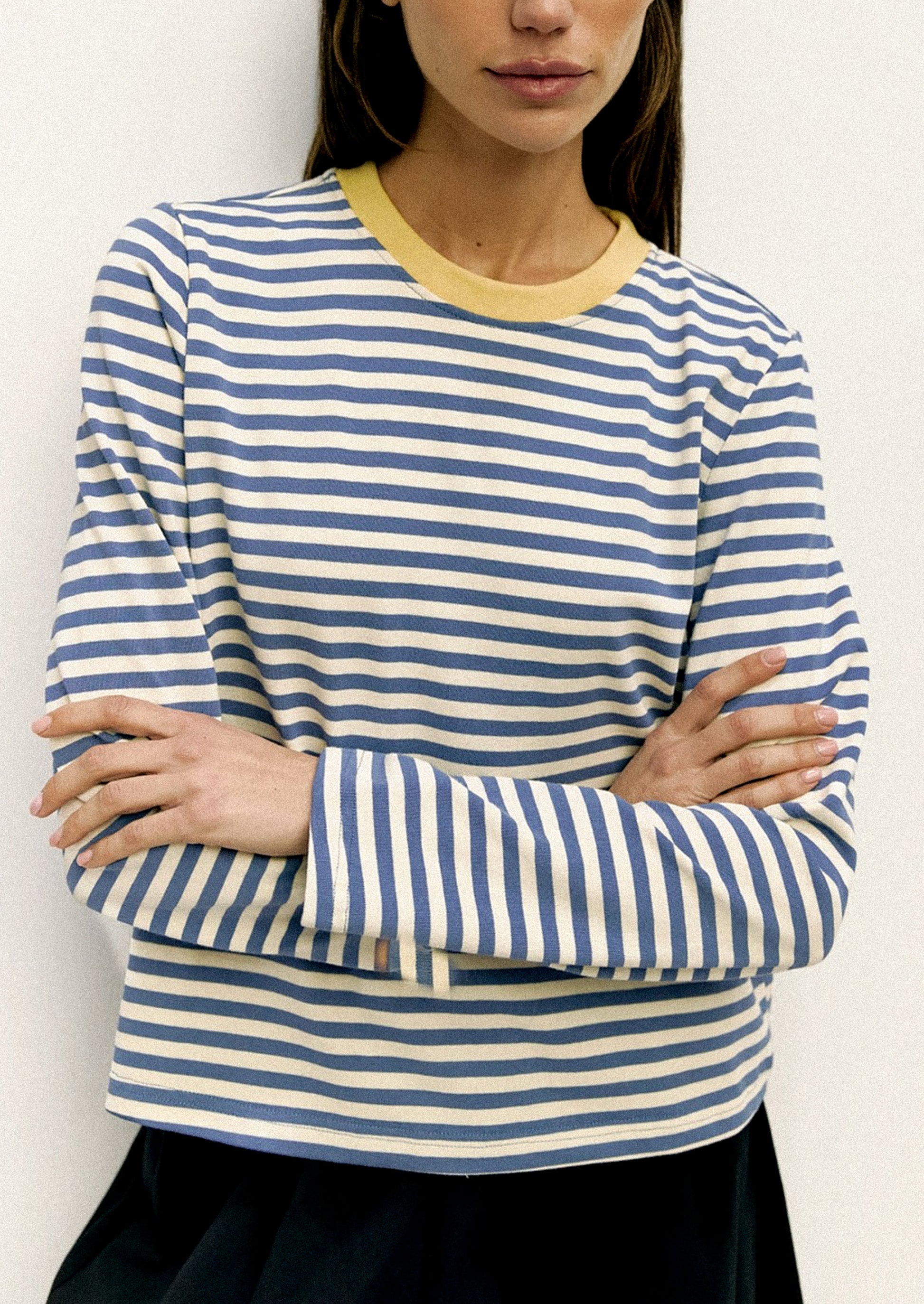 Person wearing a blue and white striped shirt with a yellow collar against a white background