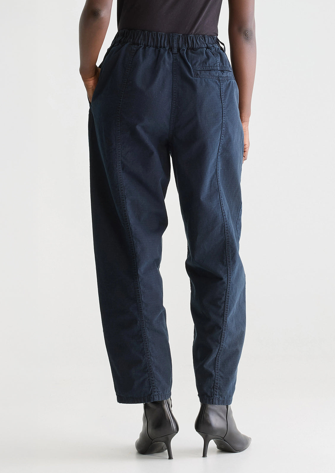A woman wearing a pair of navy blue pants with tapered leg, in ripstop cotton fabric.