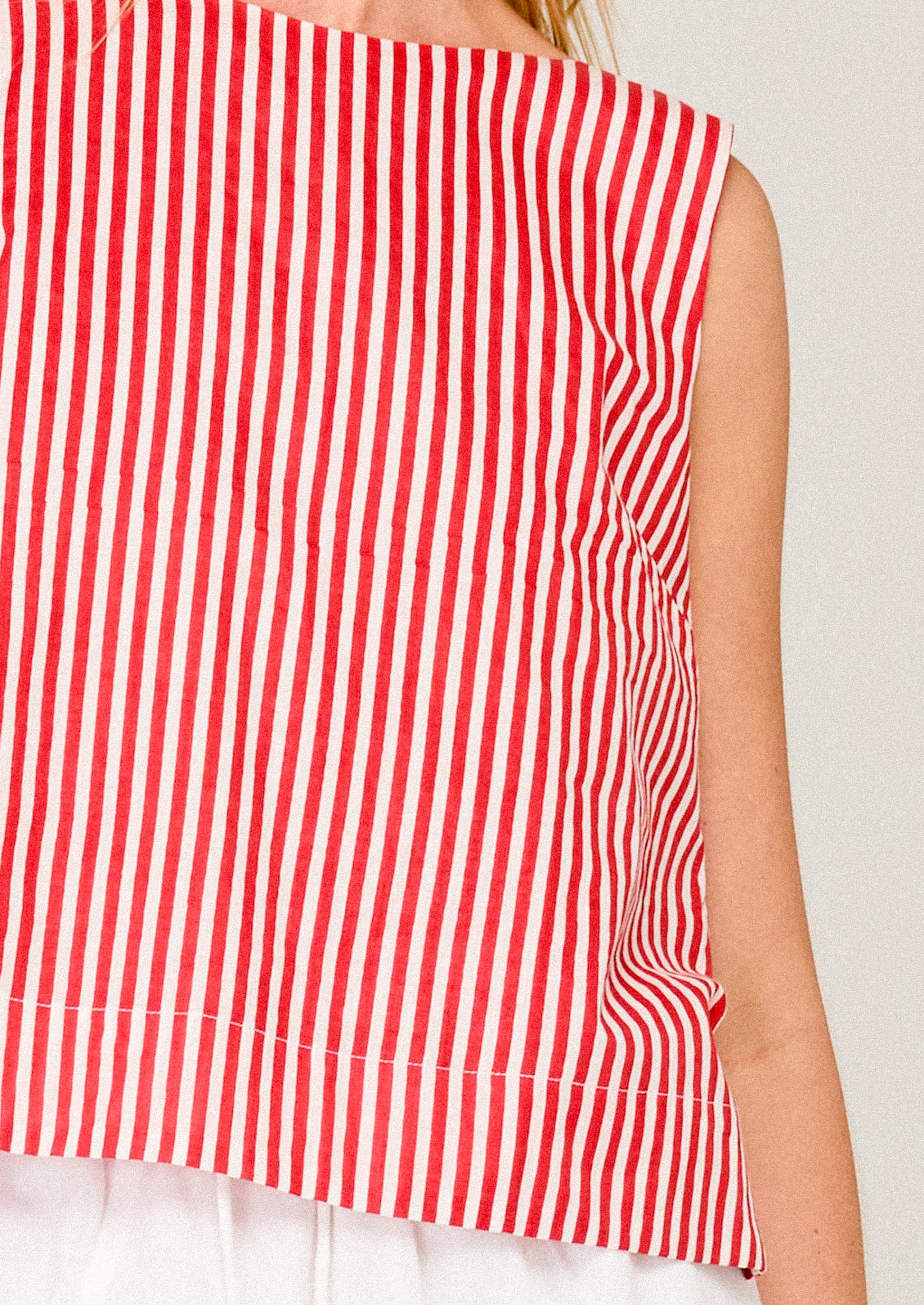 Red and white striped sleeveless top on a plain background
