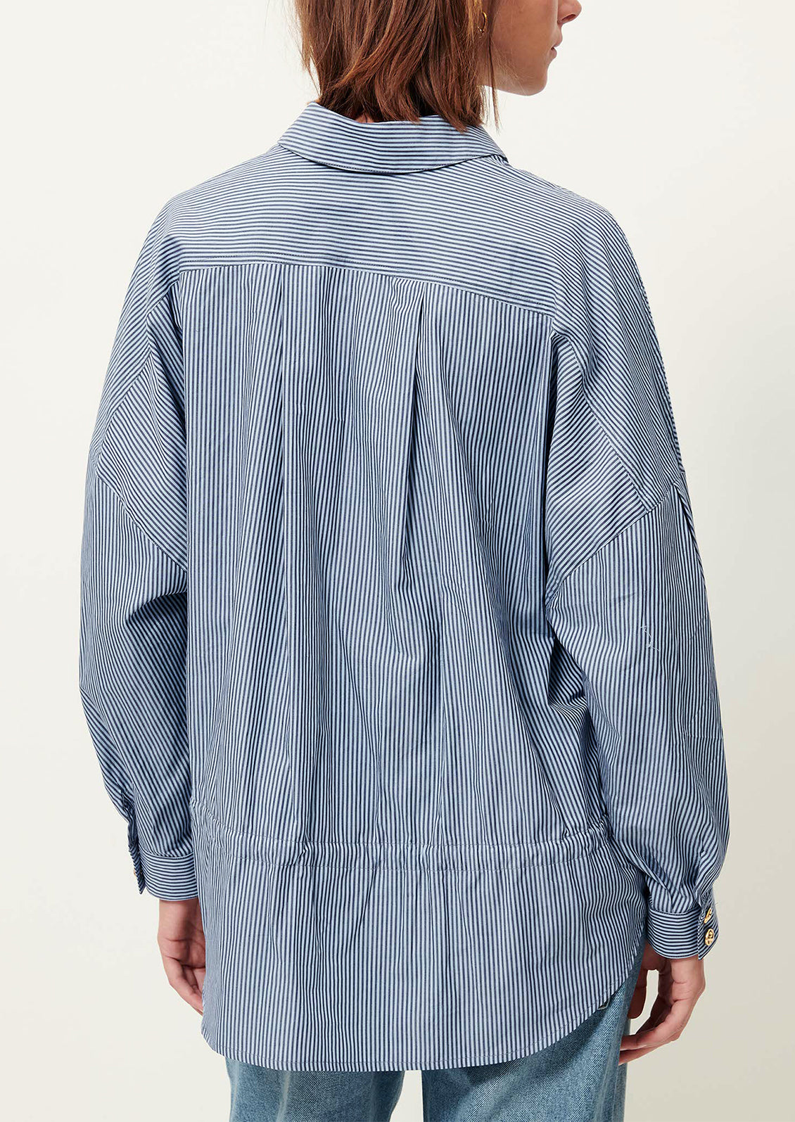 Person wearing a blue and white striped shirt with a plain background