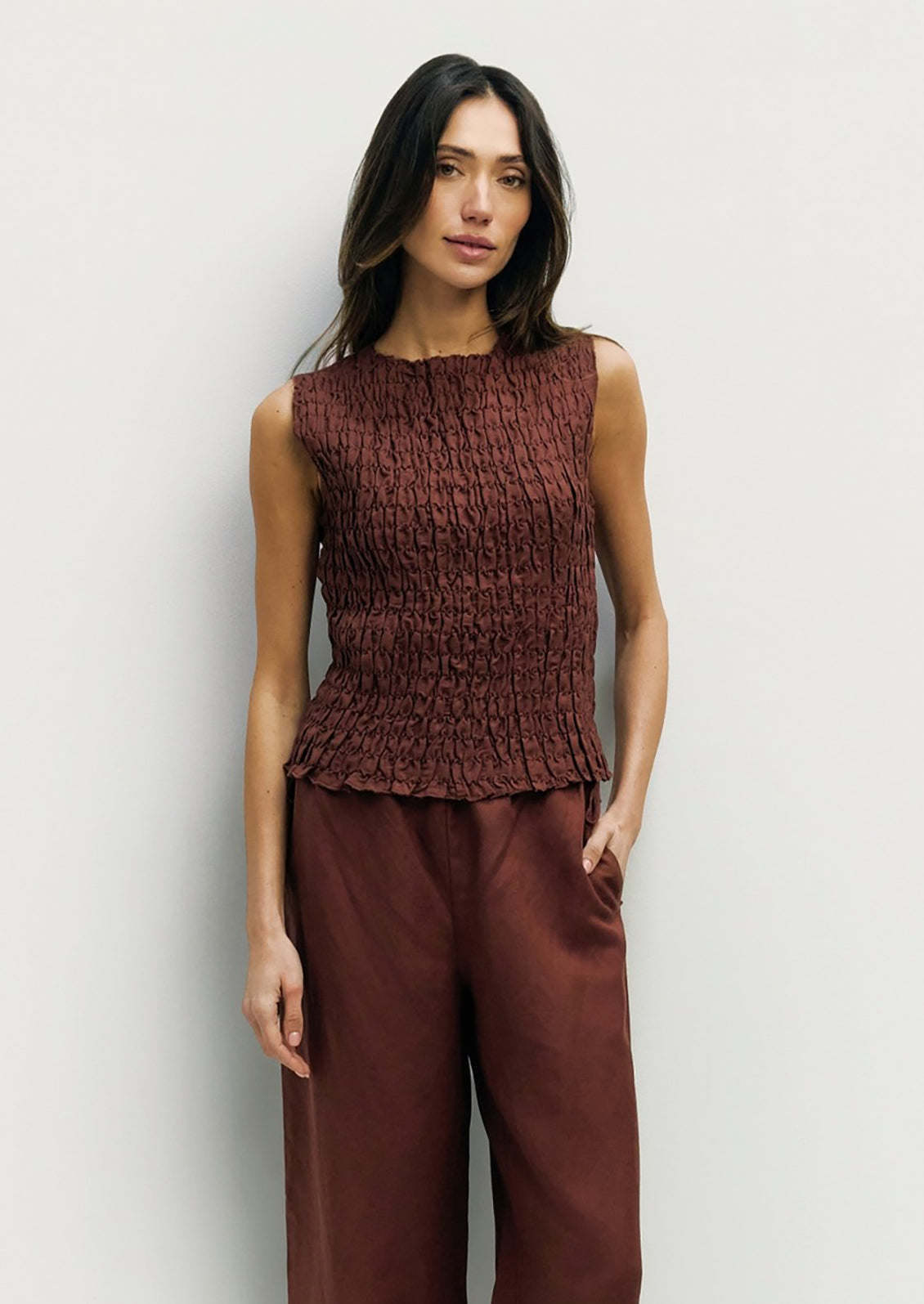 Woman wearing a brown textured top and wide-leg pants against a light background