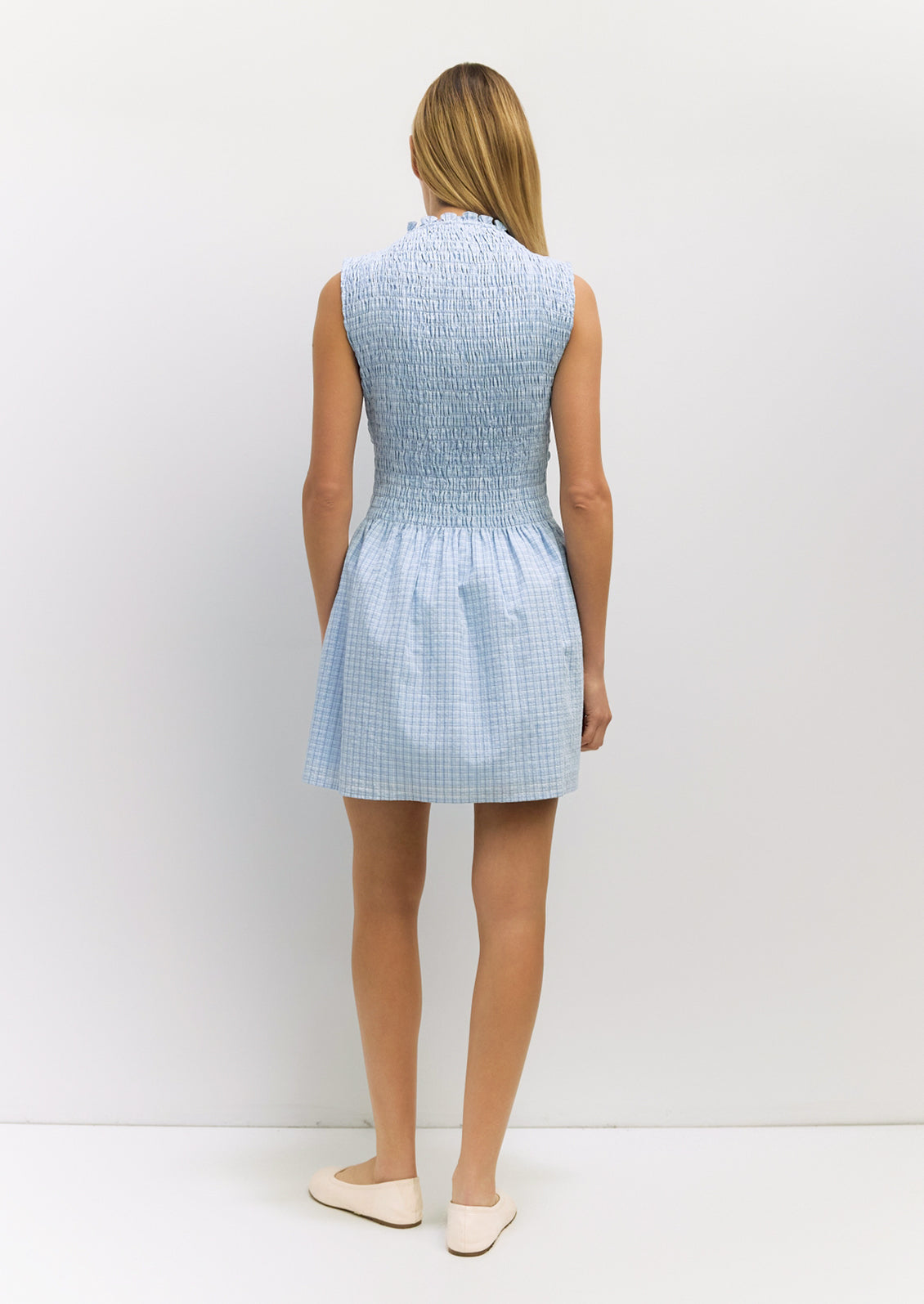 Woman wearing a light blue checkered dress against a white background