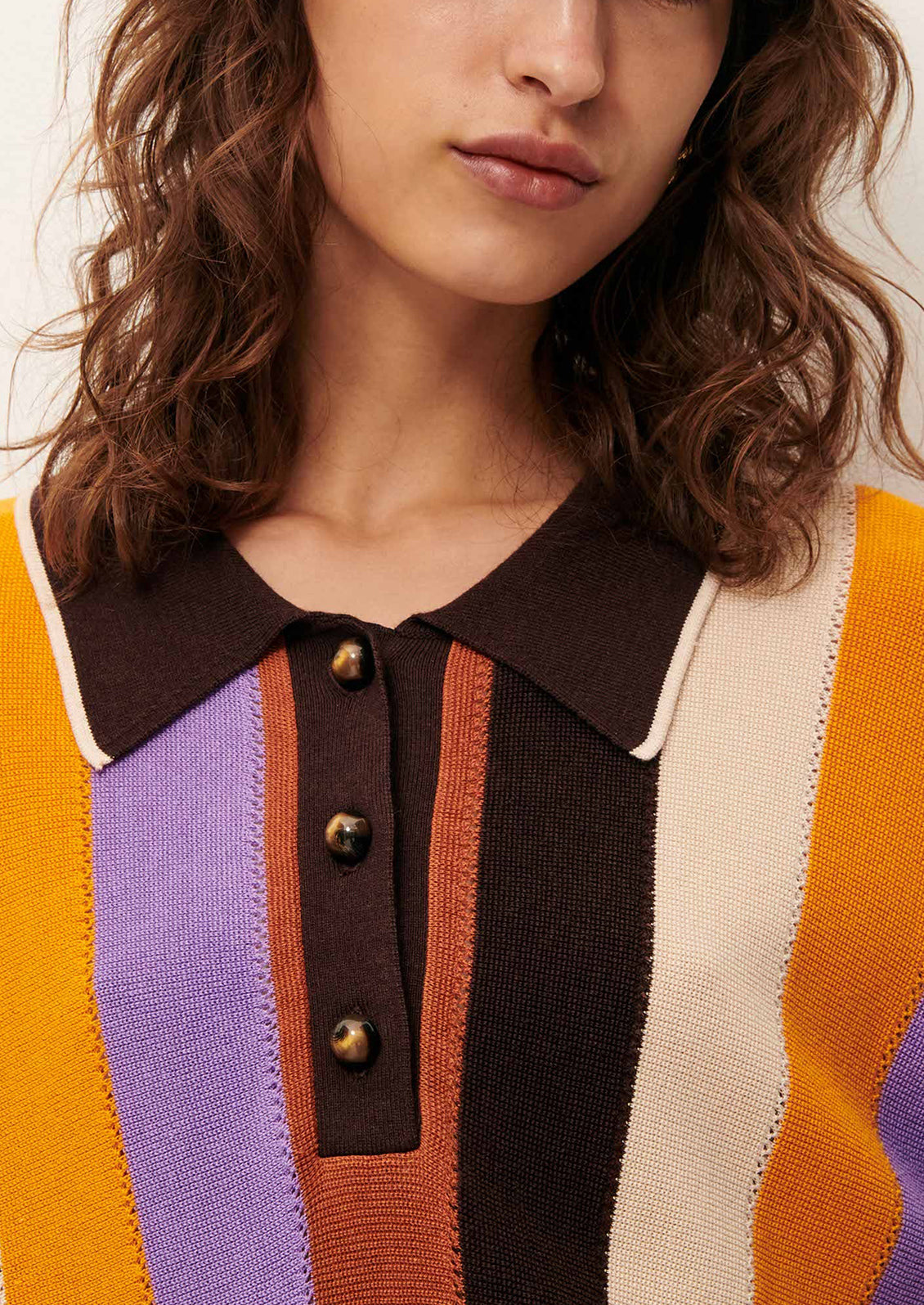 A woman wearing a colorful striped polo dress with short sleeves.