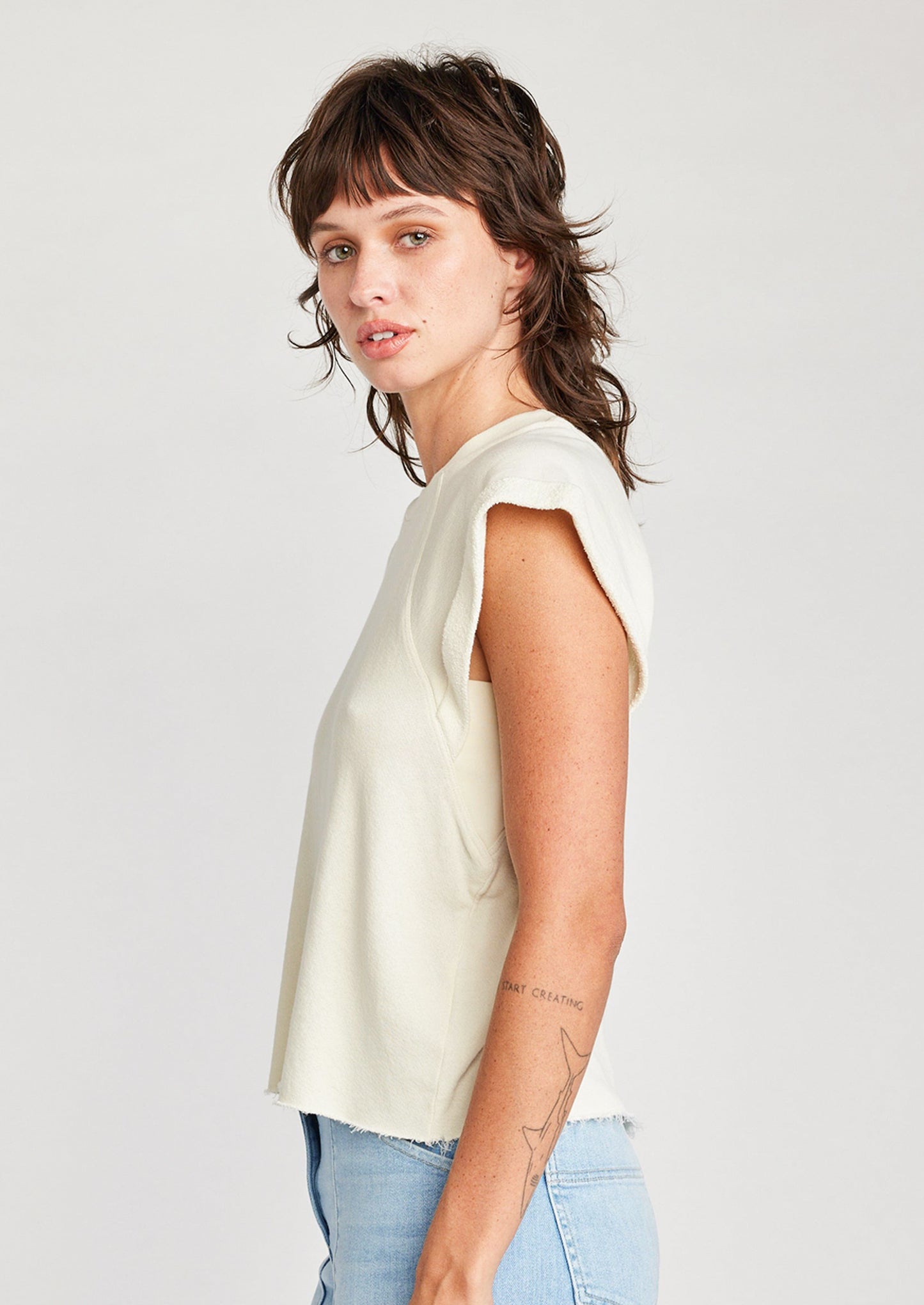 A woman wearing a raglan short sleeve sweatshirt in cream.