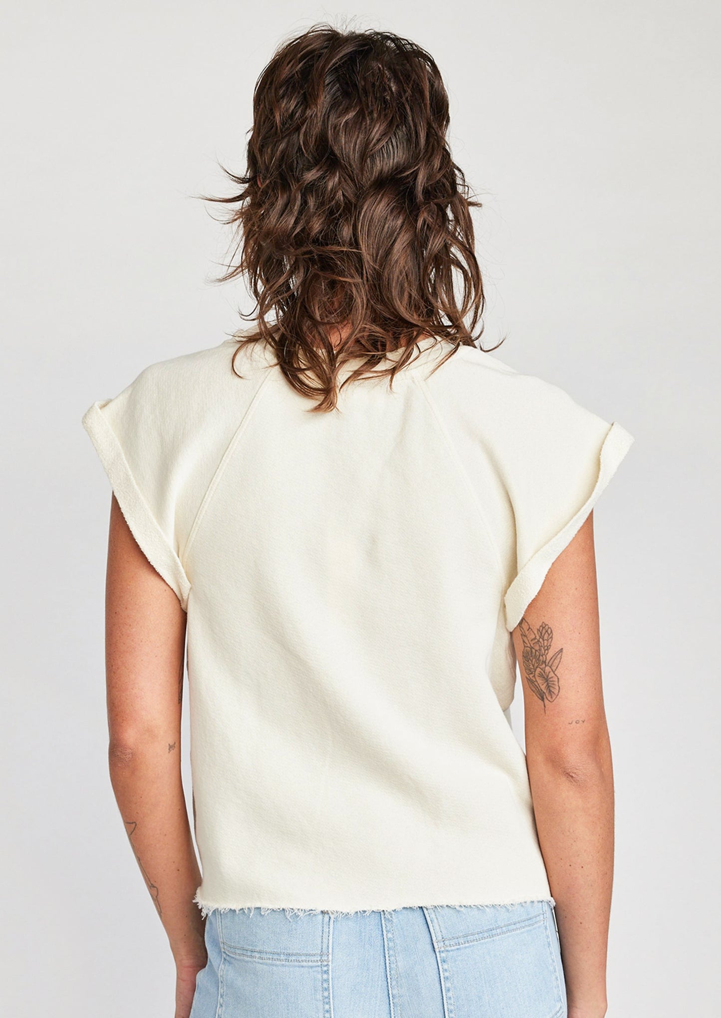 A woman wearing a raglan short sleeve sweatshirt in cream.