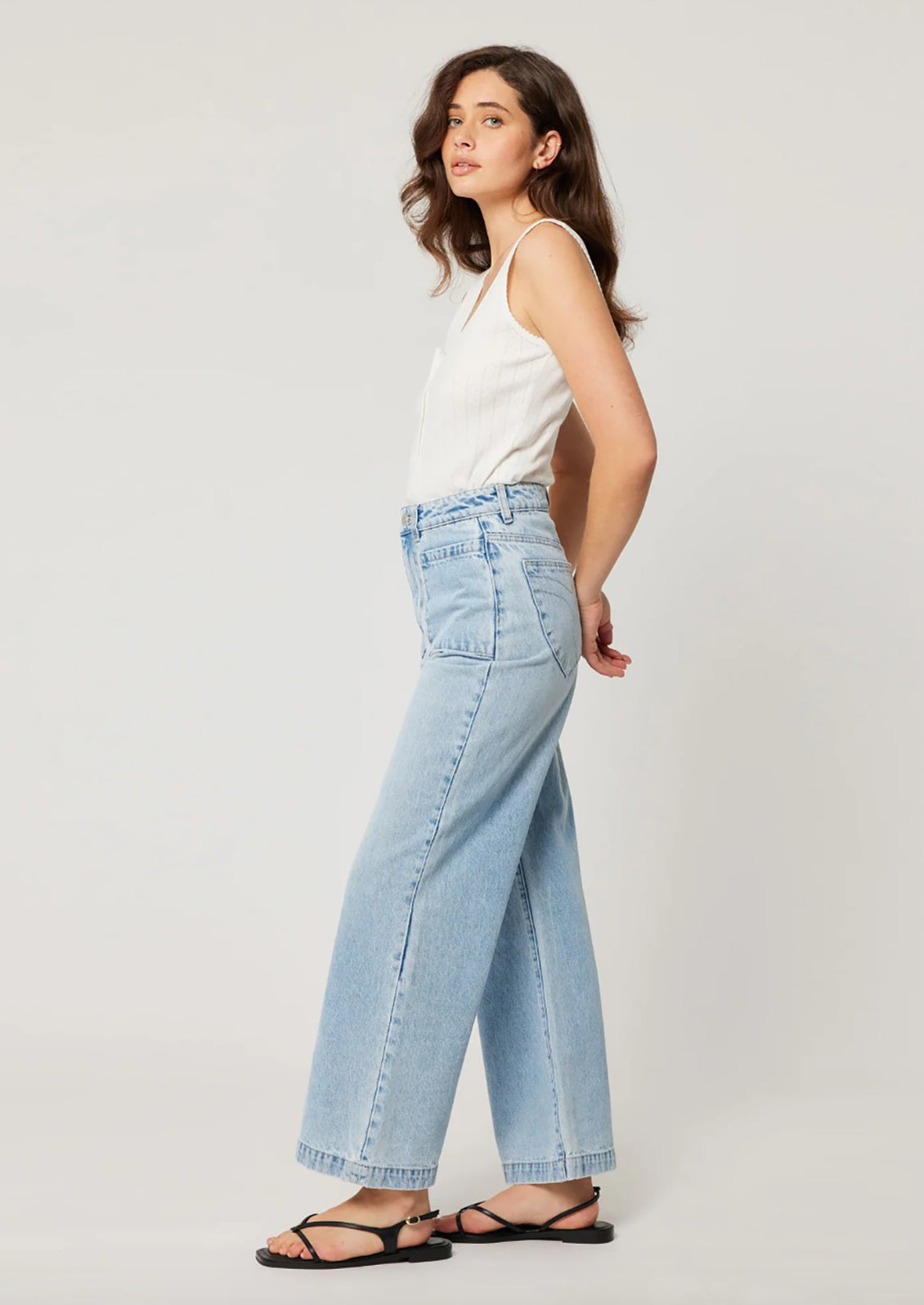 A person wearing a pair of light blue denim wide leg jeans with patch pockets at hips. 