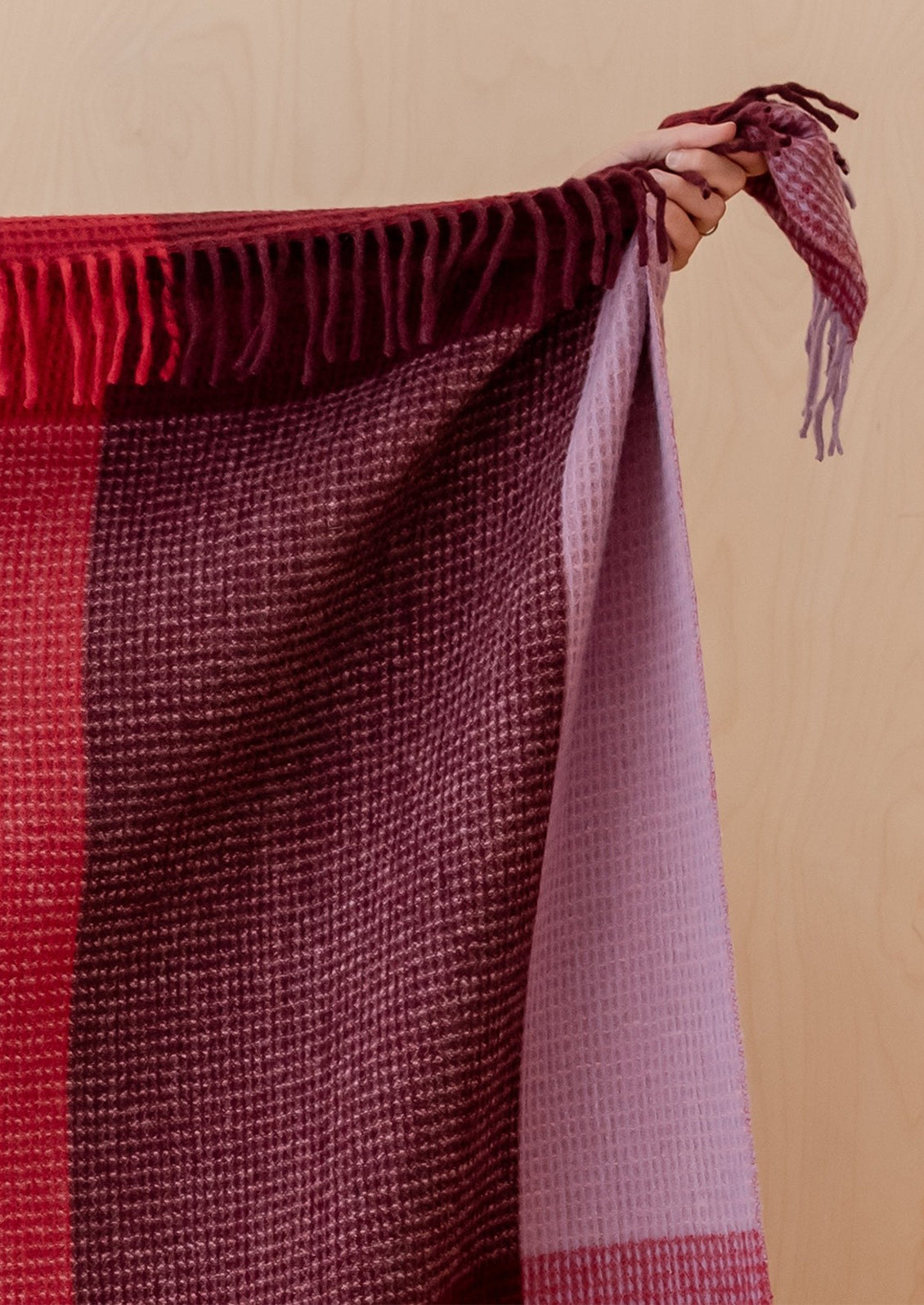 Plaid blanket with red and purple pattern on a beige background