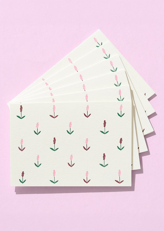 Stack of cards with floral pattern on a pink background