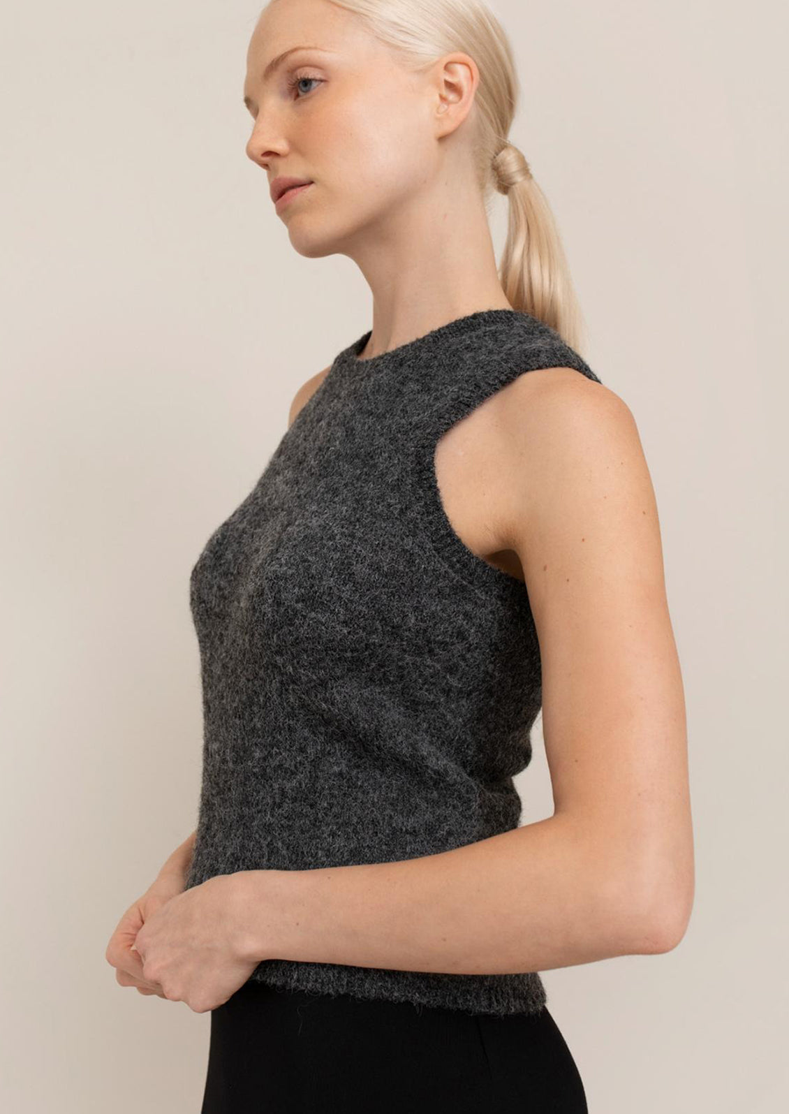 Woman wearing a dark gray sleeveless top against a plain background