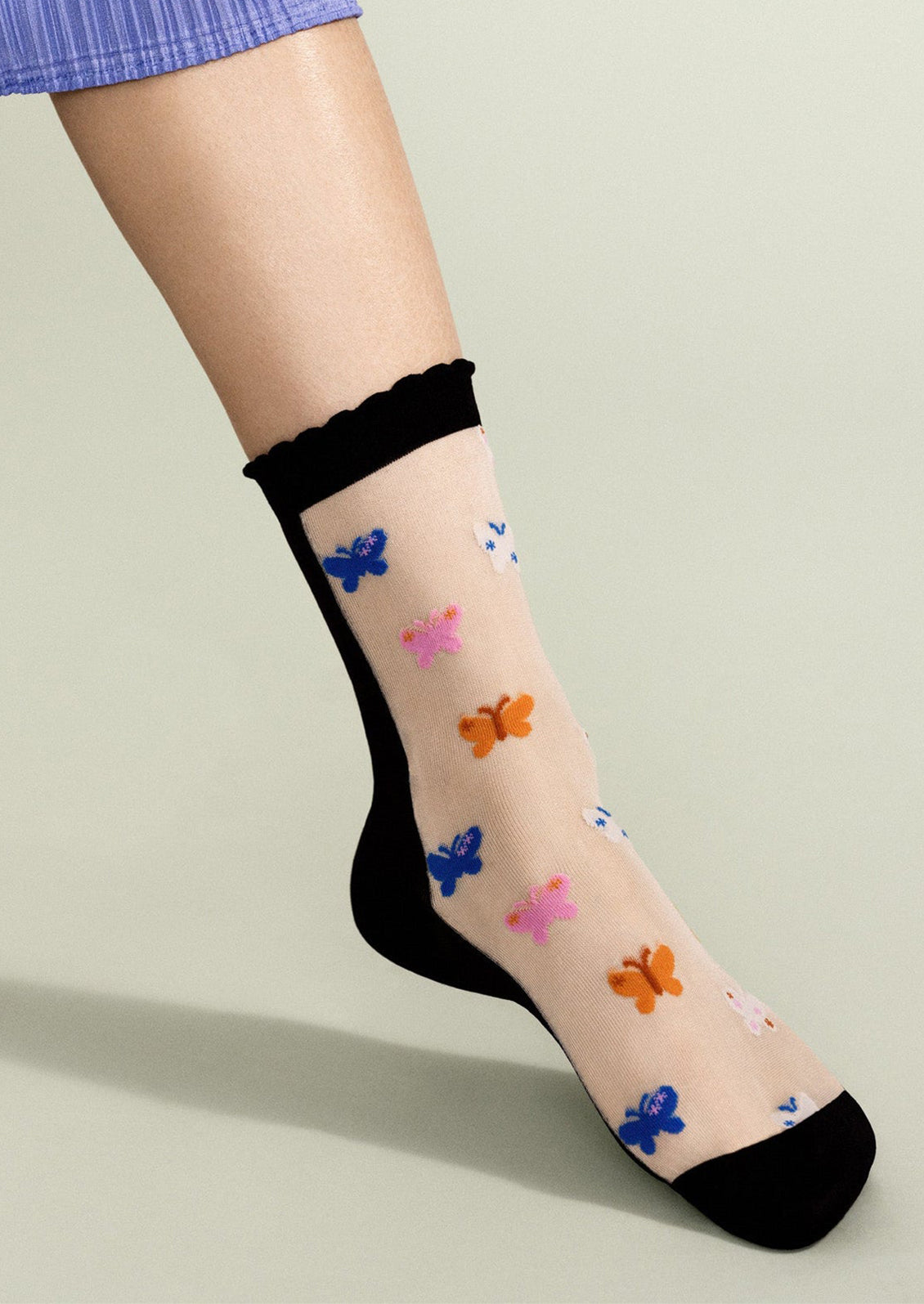 Sheer socks with colorful butterfly patterns on a neutral background