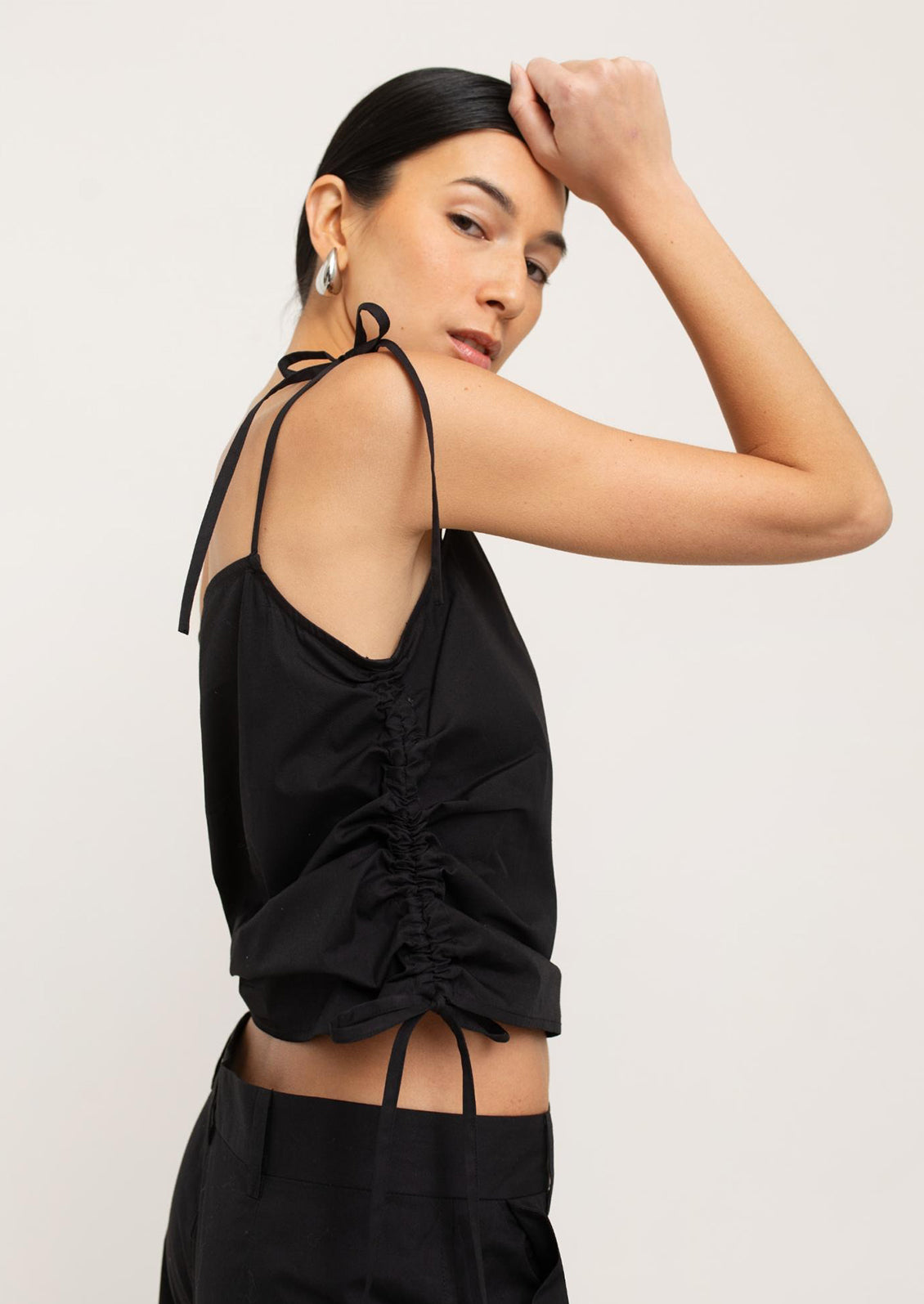 A woman wearing a black tank top with scrunched side detail.