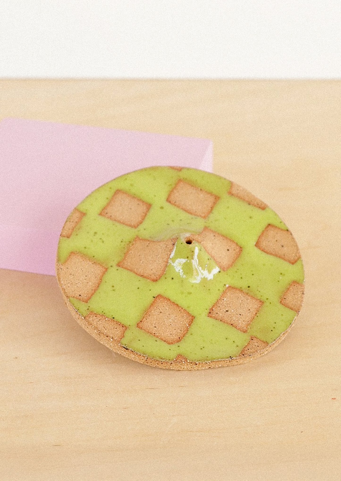 A handmade ceramic incense holder in green checkered pattern.