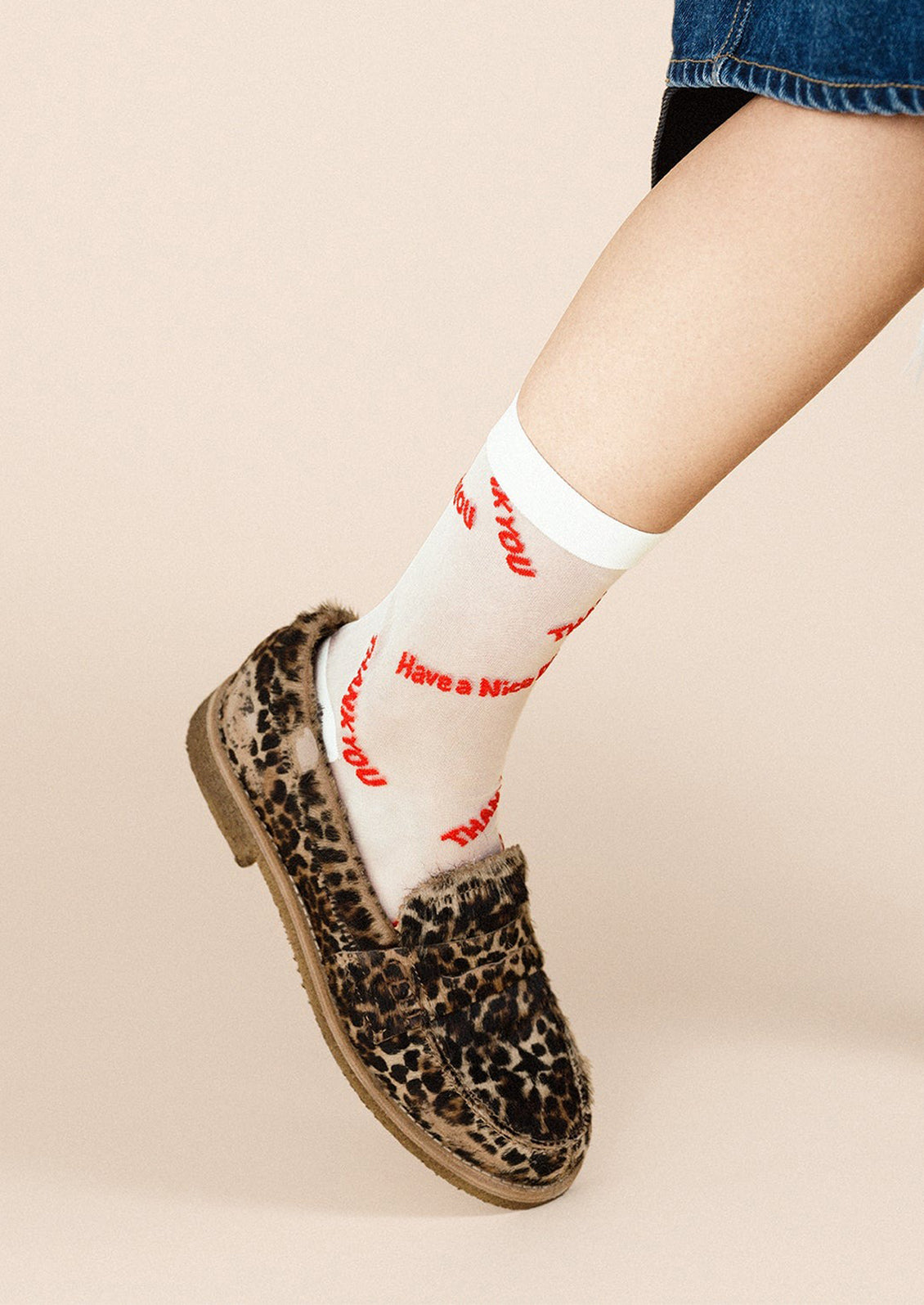 A pair of semi-sheer white socks with red lettering throughout "Have a nice day Thank You".