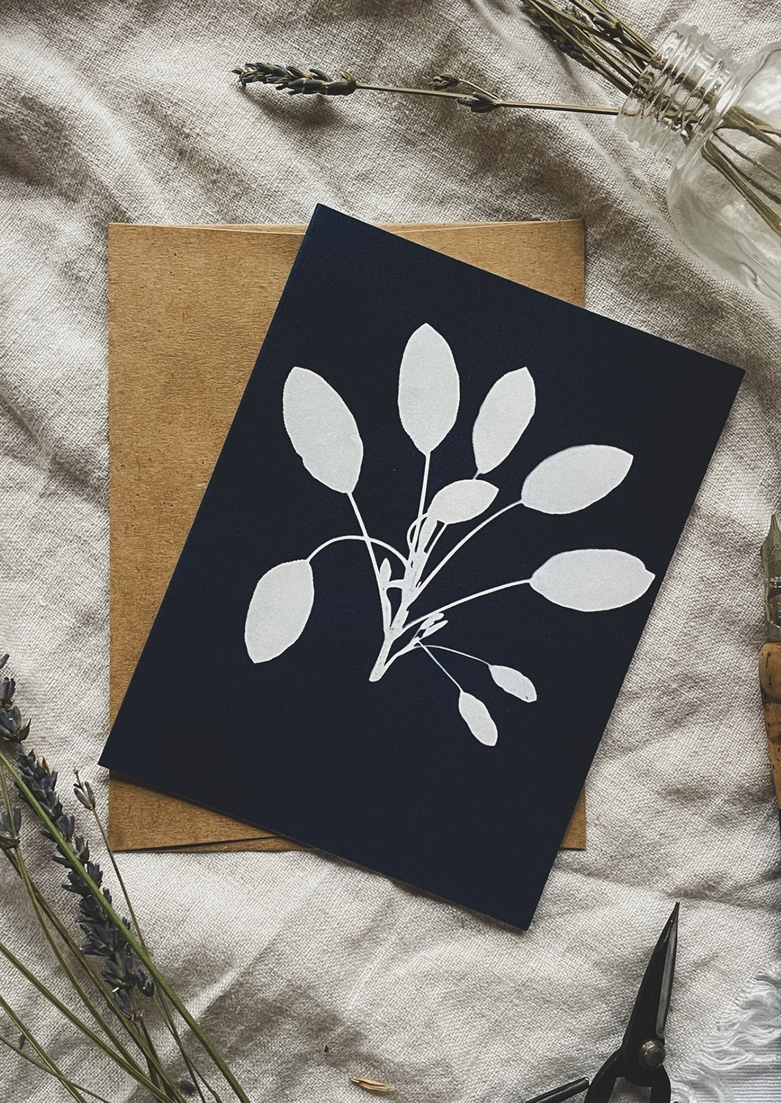 Black card with white sage design on a textured surface with dried lavender.
