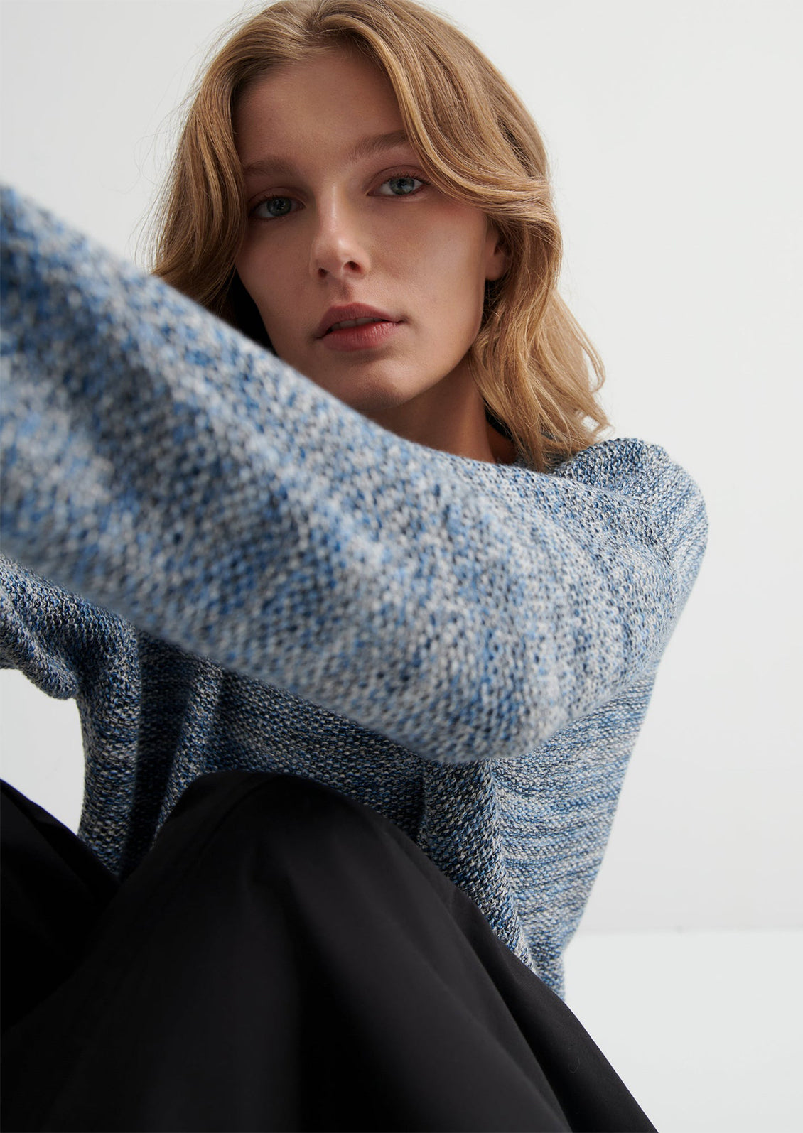 Woman wearing a blue knitted sweater against a white background