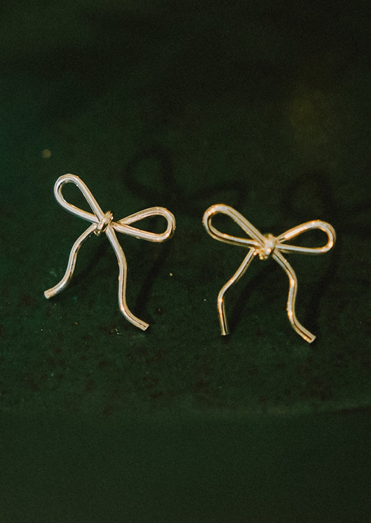 A pair of small handmade earrings in bow shape made from gold wire.