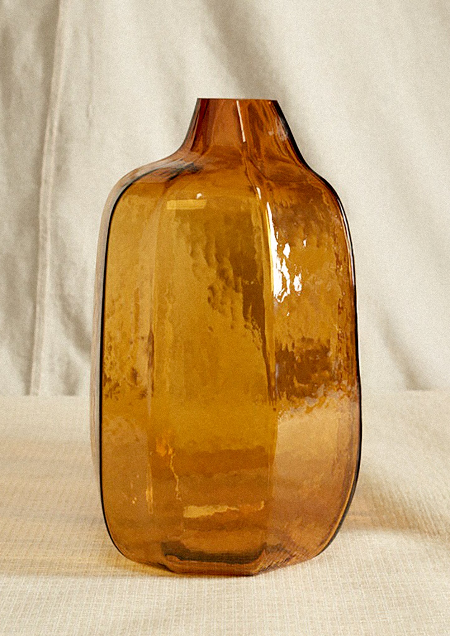 Brown glass vase on a beige fabric background