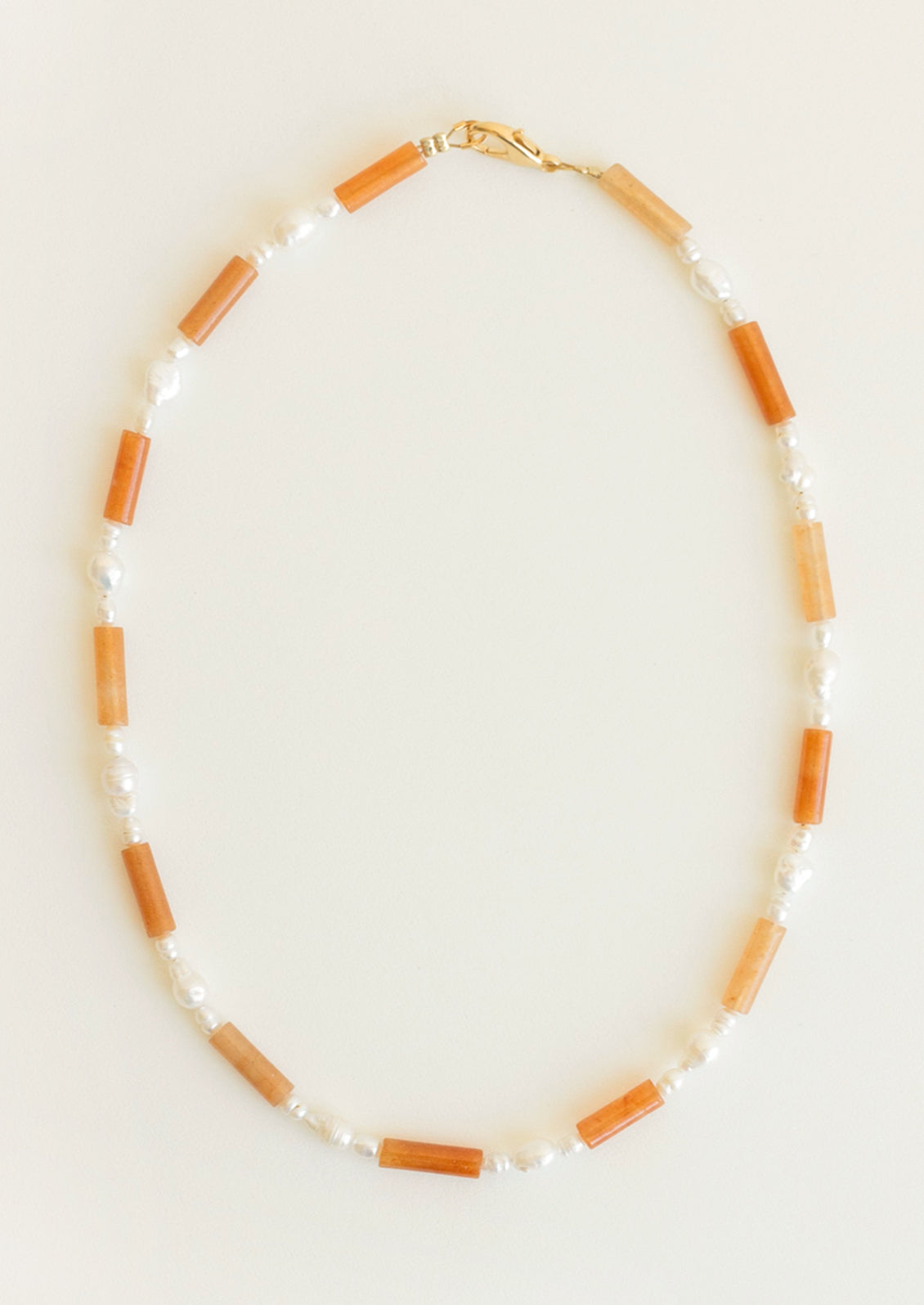 Necklace with orange and white beads on a light background