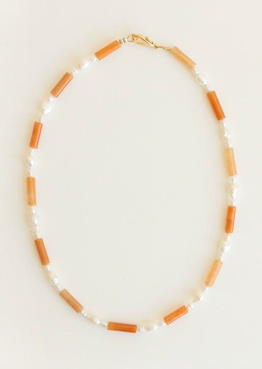 Necklace with orange and white beads on a light background