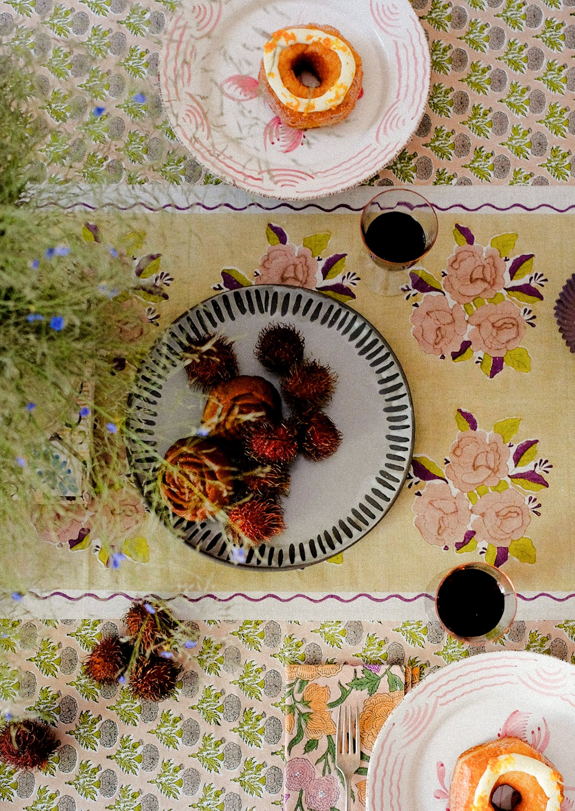 A linen table runner with pale yellow floral pattern and wavy purple border.