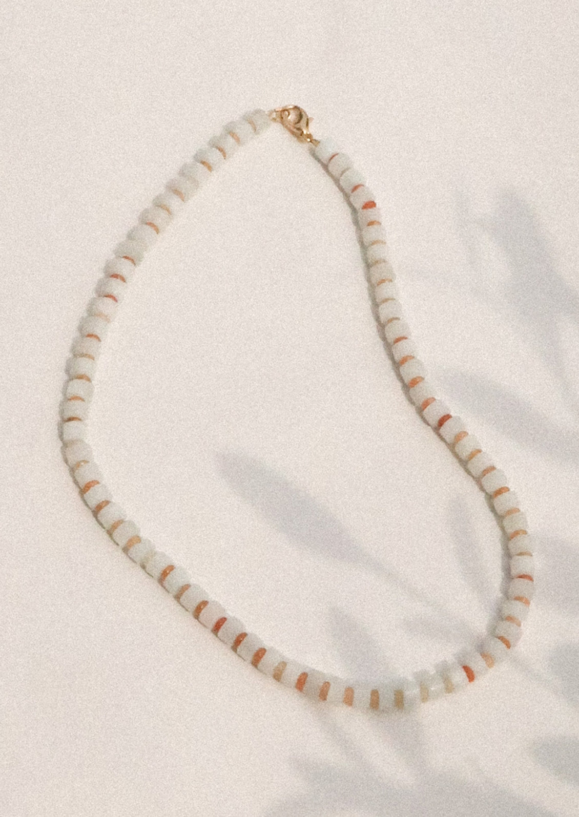 Necklace with white and orange beads on a light background
