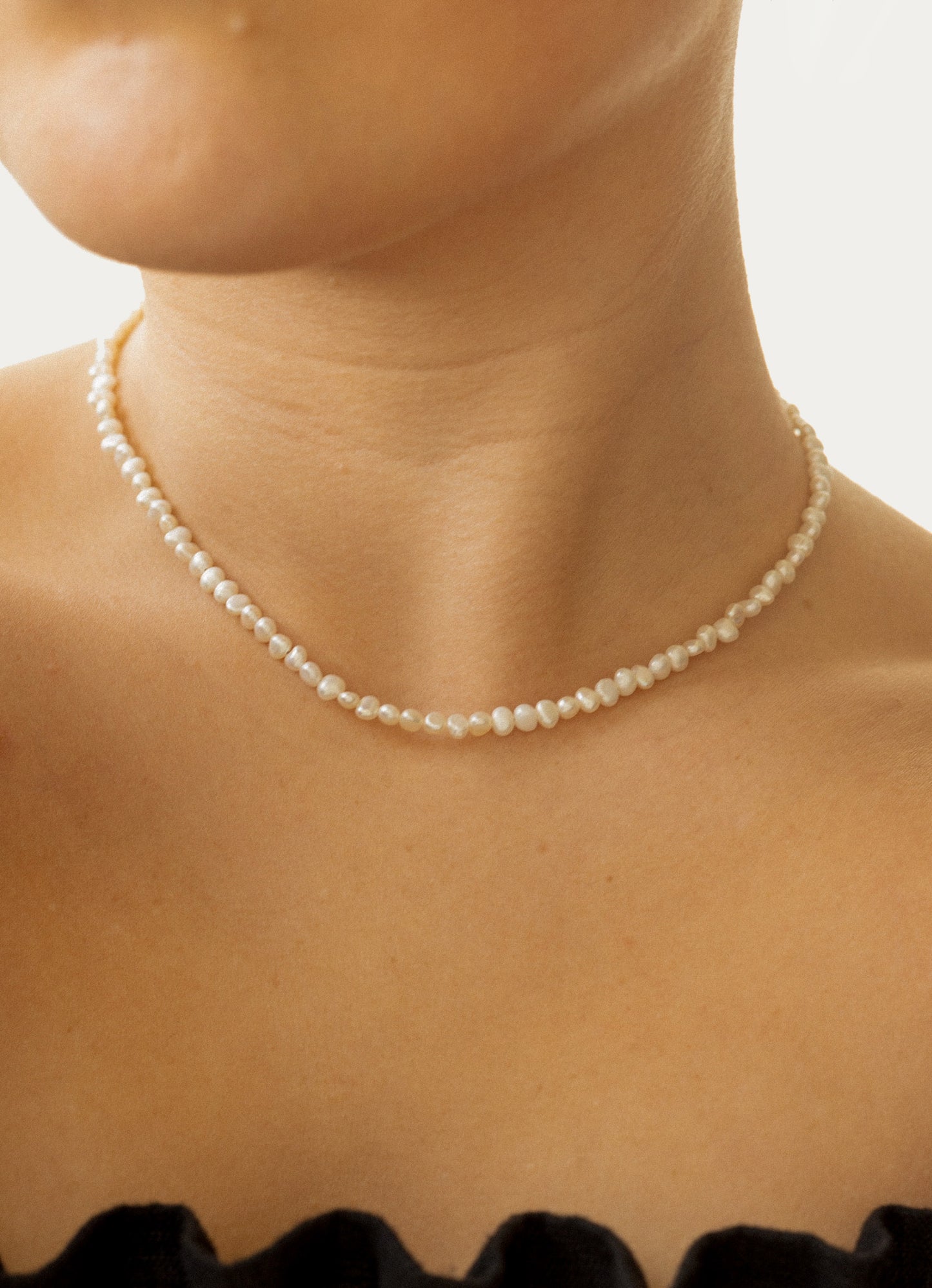 Pearl necklace worn by a person with a neutral background