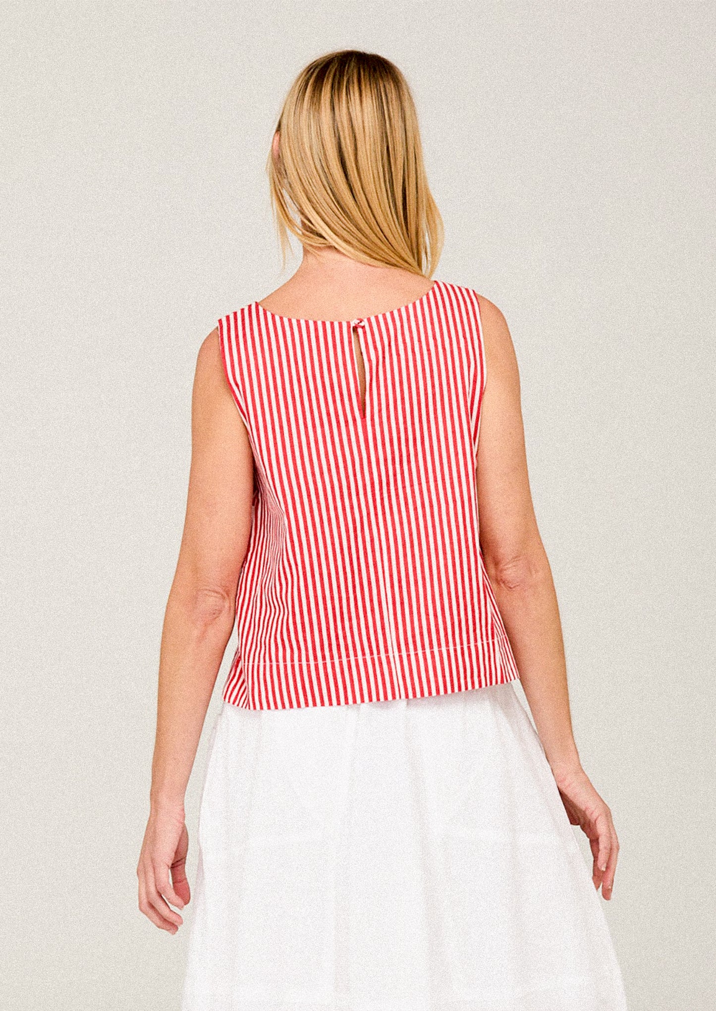 Woman wearing a red and white striped sleeveless top against a plain background